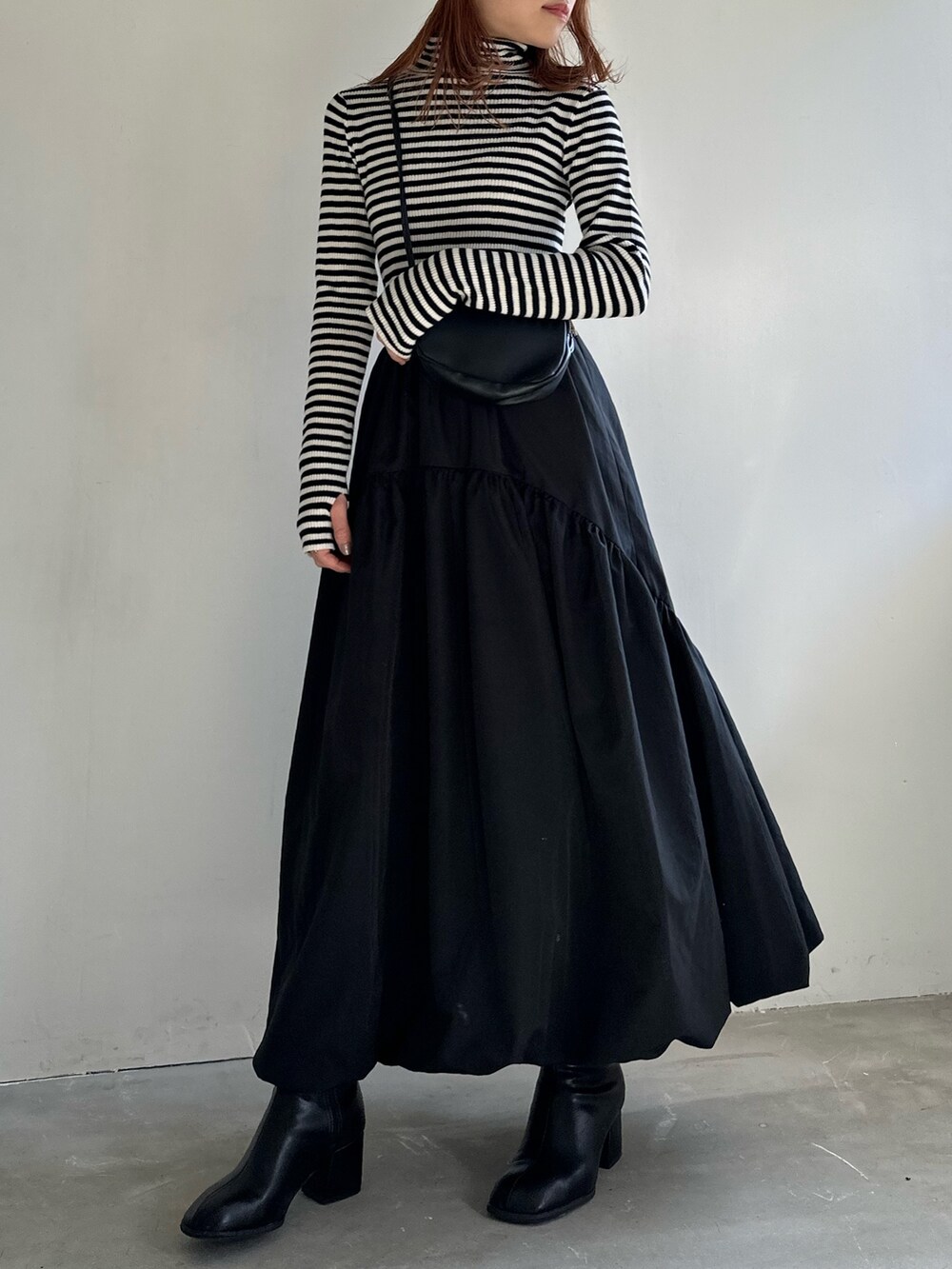 ブラック系のスカート、ブラック系のショルダーバッグ、ブラック系のブーツを着用したレディースの冬コーディネートの3枚目の写真