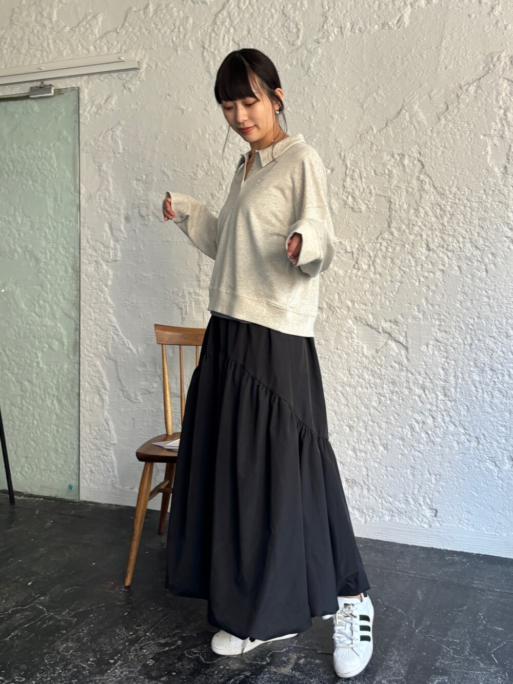ブラック系のスカート、ホワイト系のスニーカー、ベージュ系のポロシャツを着用したレディースの冬コーディネートの5枚目の写真