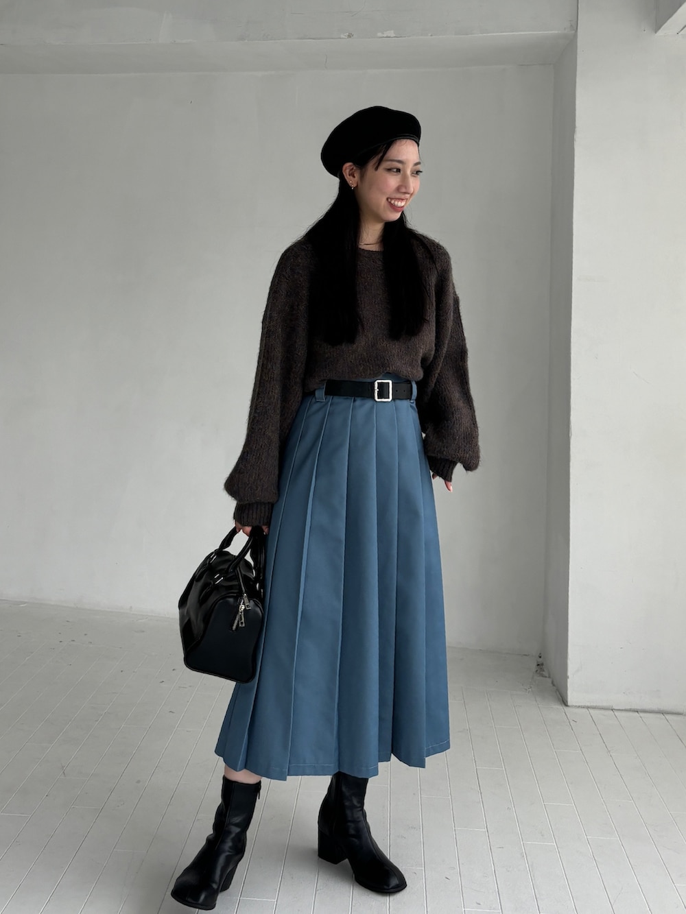 ブラウン系のニット/セーター、ブルー系のスカート、ブラック系のブーツを着用したレディースの秋コーディネートの2枚目の写真