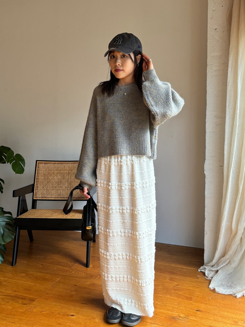ベージュ系のニット/セーター、ホワイト系のスカート、ブラック系のスニーカーを着用したレディースの秋コーディネートの2枚目の写真