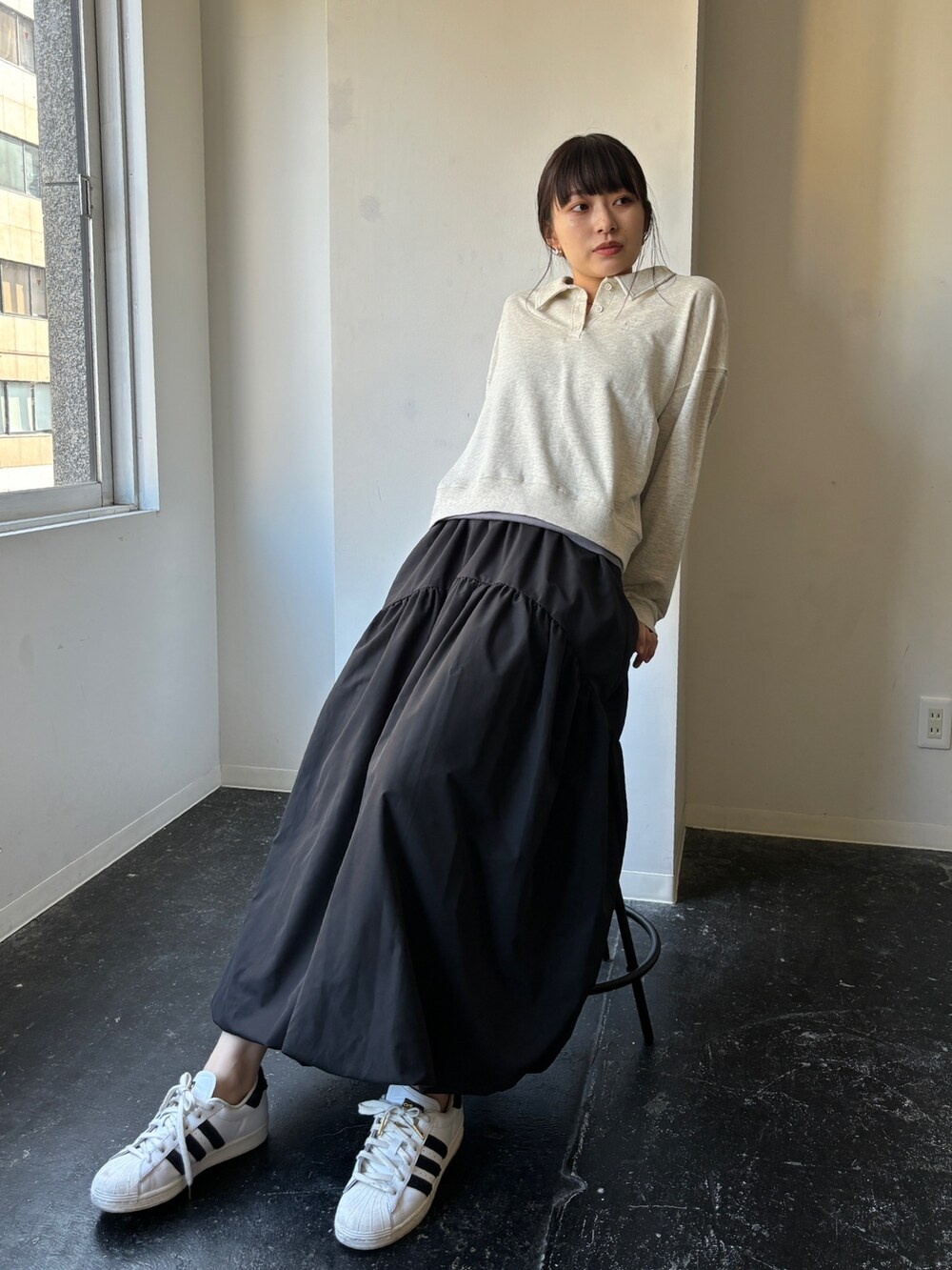 ブラック系のスカート、ホワイト系のスニーカー、ベージュ系のポロシャツを着用したレディースの冬コーディネートの3枚目の写真