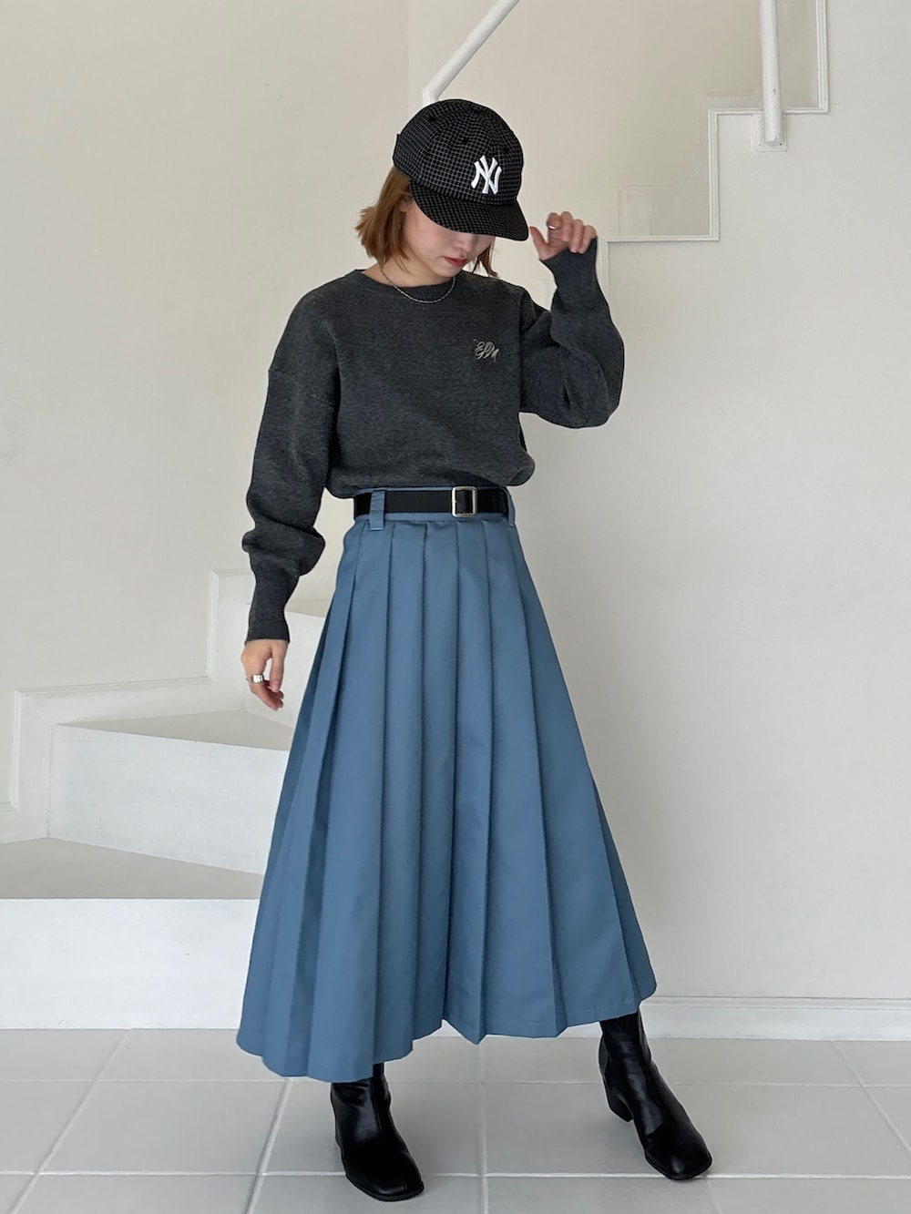 ブルー系のスカート、グレー系のニット/セーター、ブラウン系のブーツを着用したレディースの冬コーディネートの2枚目の写真