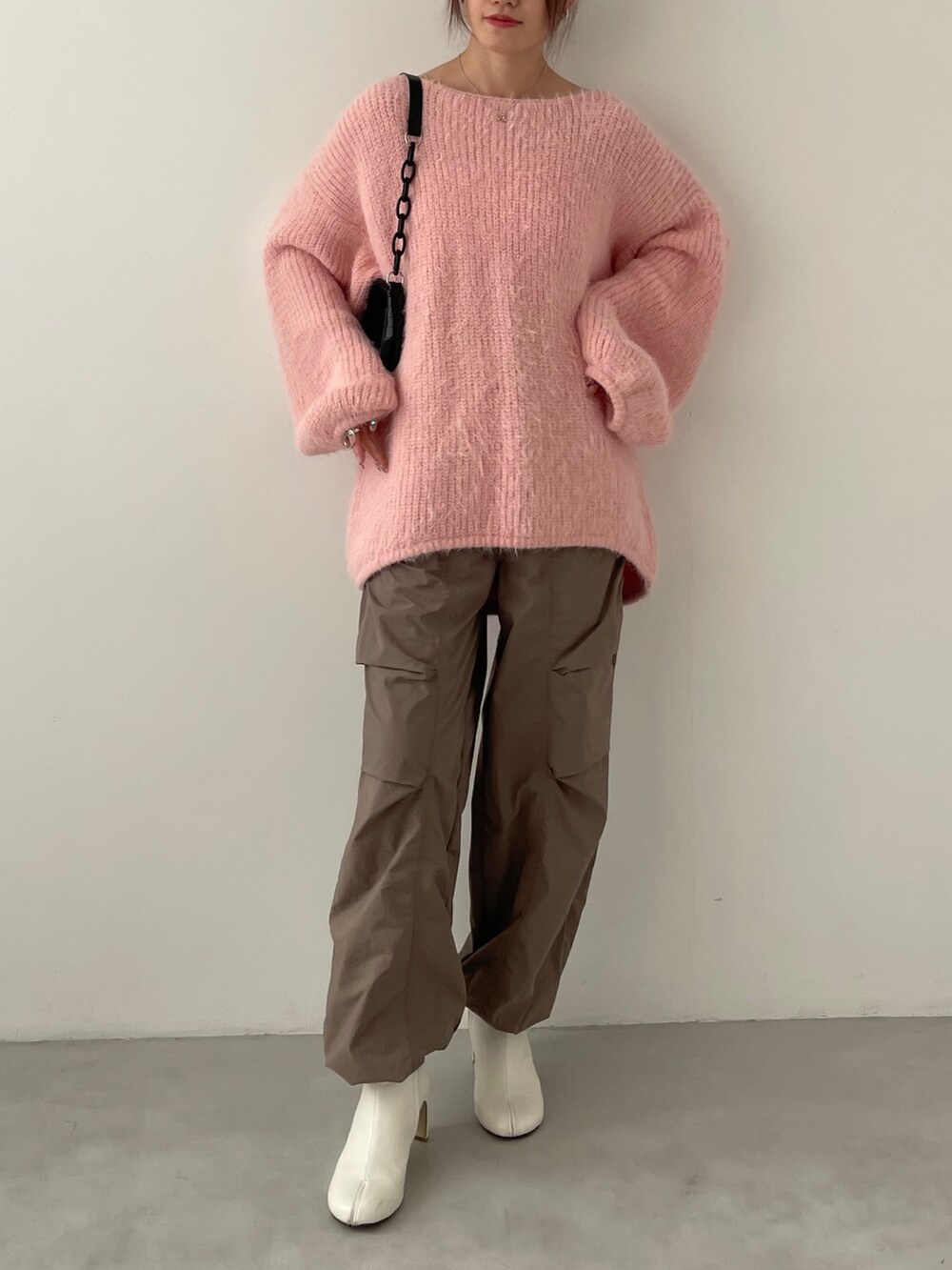 グレー系のデニムパンツ、グリーン系のニット/セーター、ブラック系のスニーカーを着用したレディースの冬コーディネートの2枚目の写真