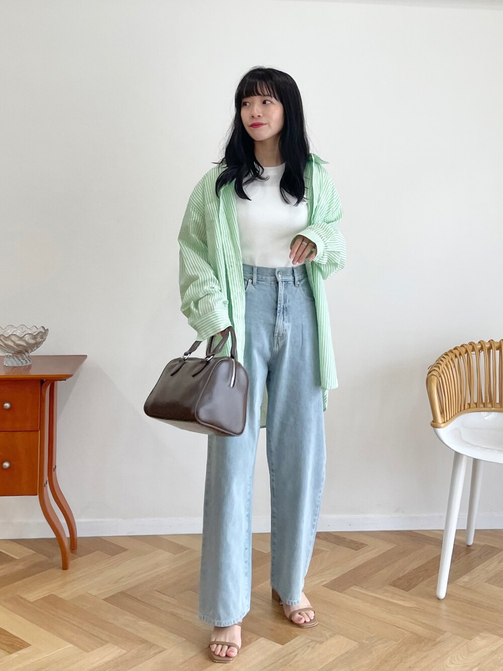 ブラウン系のボストンバッグ、ブルー系のデニムパンツ、ホワイト系のTシャツ/カットソーを着用したレディースの夏コーディネートの2枚目の写真