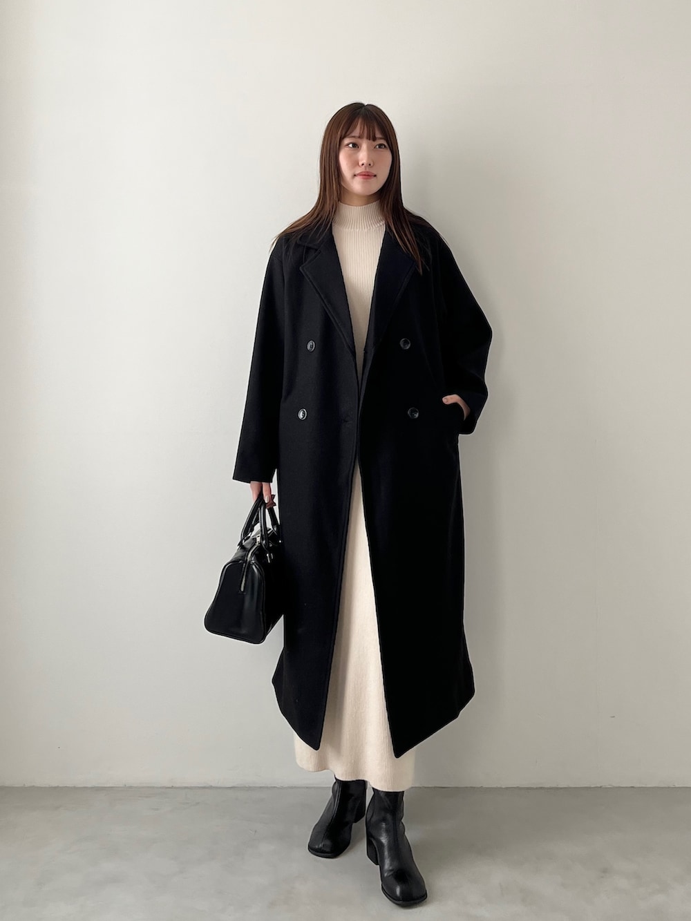 ブルー系のチェスターコート、ホワイト系のニット/セーター、グレー系のスウェットパンツを着用したレディースの冬コーディネートの3枚目の写真