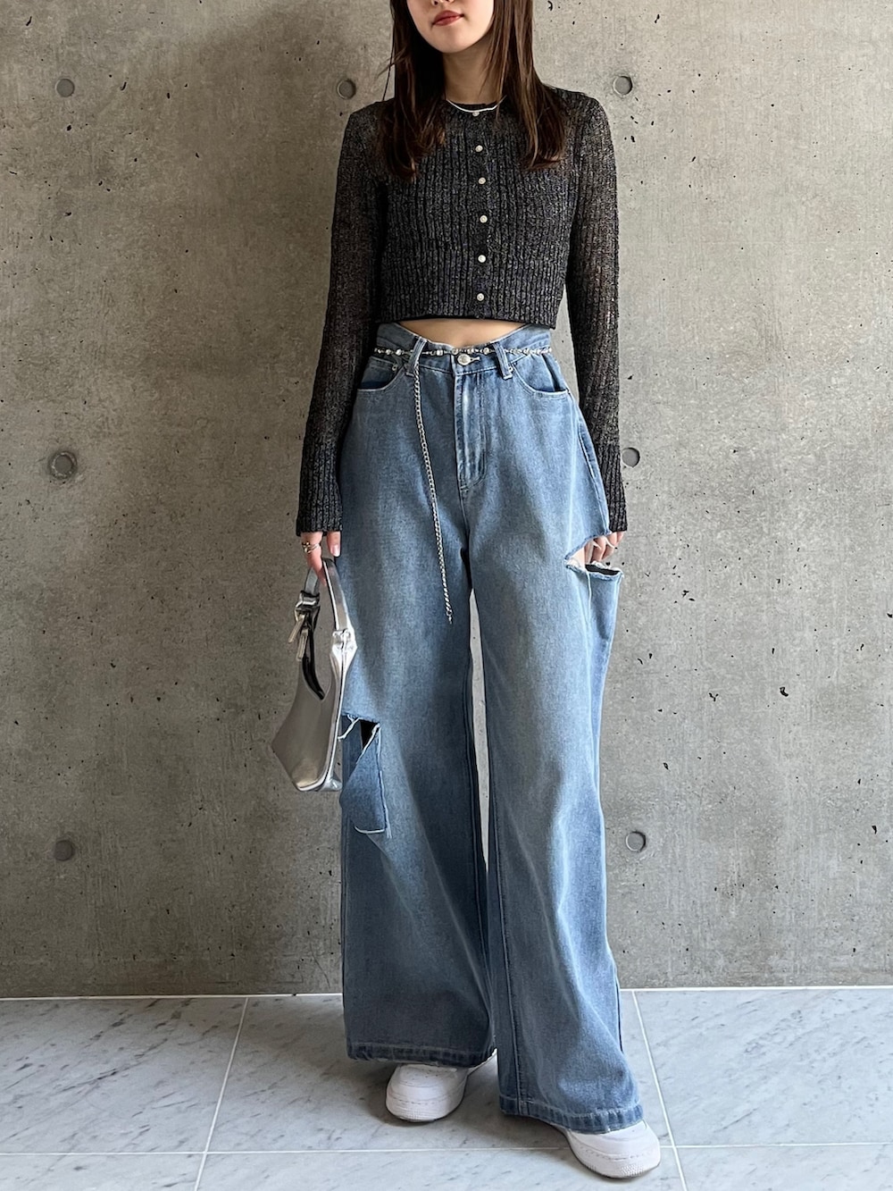 ブルー系のデニムパンツ、ブラック系のカーディガン/ボレロ、ホワイト系のスニーカーを着用したレディースの春コーディネートの3枚目の写真