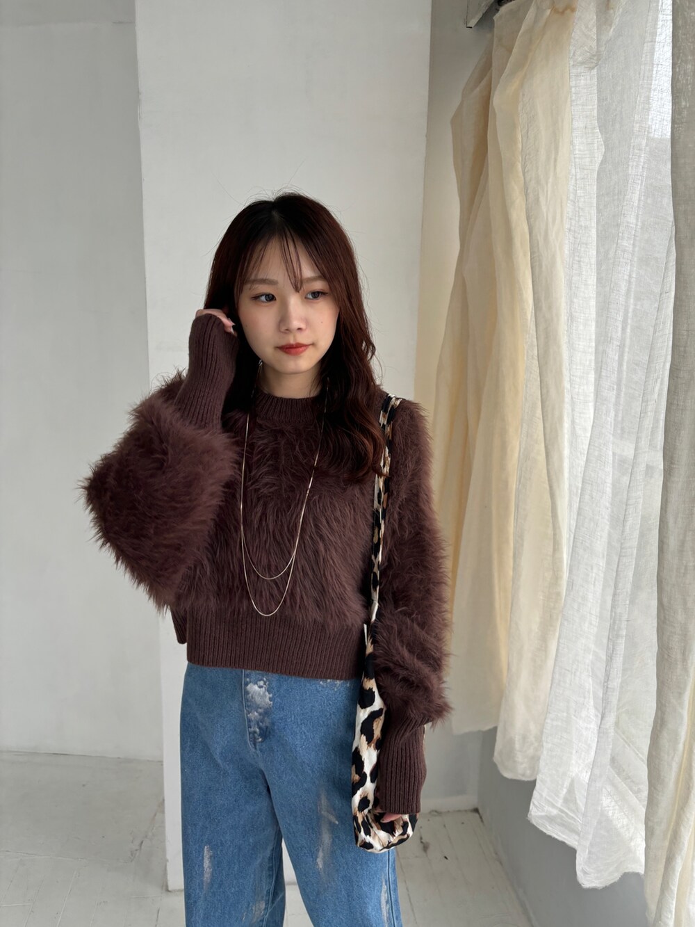 ブラウン系のニット/セーター、ブルー系のデニムパンツ、ホワイト系のスニーカーを着用したレディースの秋コーディネートの3枚目の写真