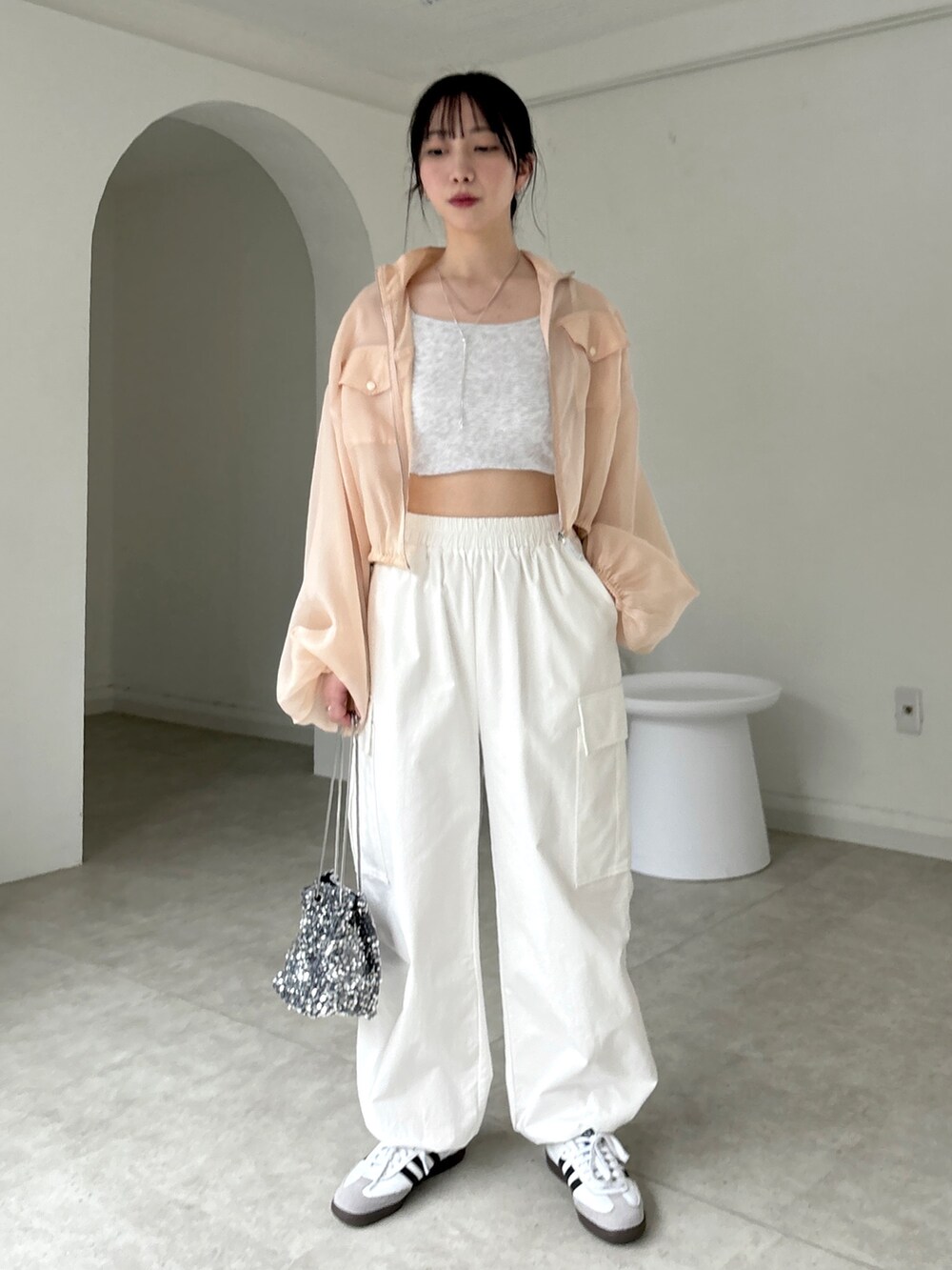 ホワイト系のカーゴパンツ、ホワイト系のスニーカー、ベージュ系のタンクトップを着用したレディースの春コーディネートの4枚目の写真