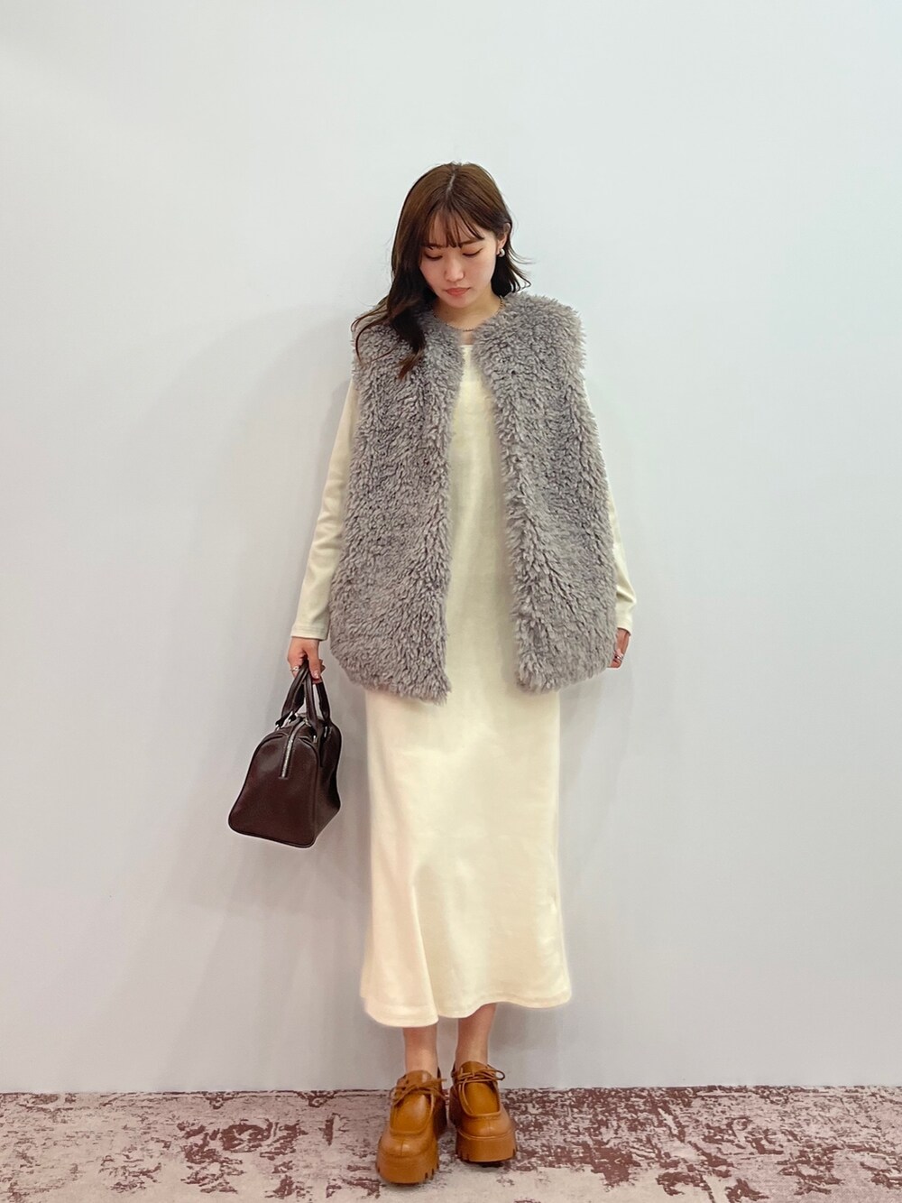 ホワイト系のワンピース、グレー系のベスト、ブラック系のボストンバッグを着用したレディースの秋コーディネートの2枚目の写真