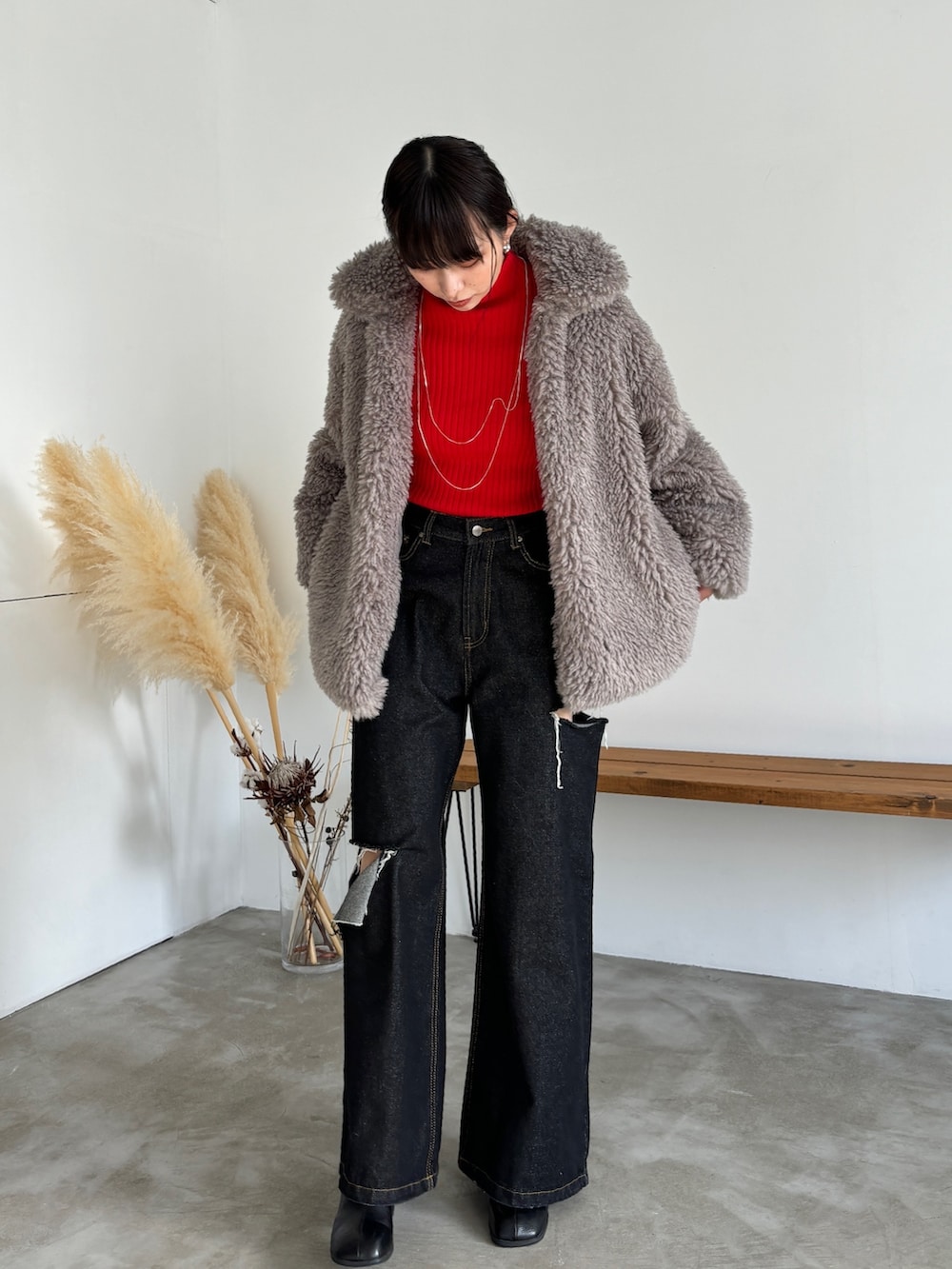 ブラック系のデニムパンツ、ブラック系のブーツ、レッド系のニット/セーターを着用したレディースの冬コーディネートの4枚目の写真