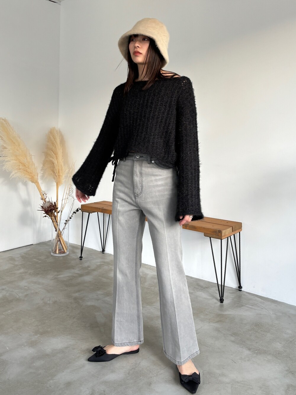 グレー系のデニムパンツ、ブラック系のニット/セーター、ベージュ系のハットを着用したレディースの冬コーディネートの2枚目の写真