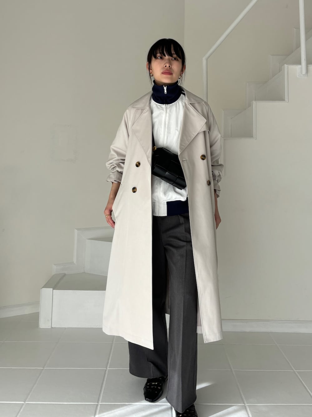 グレー系のトレンチコート、ホワイト系のその他アウター、グレー系のスラックスを着用したレディースの冬コーディネートの4枚目の写真