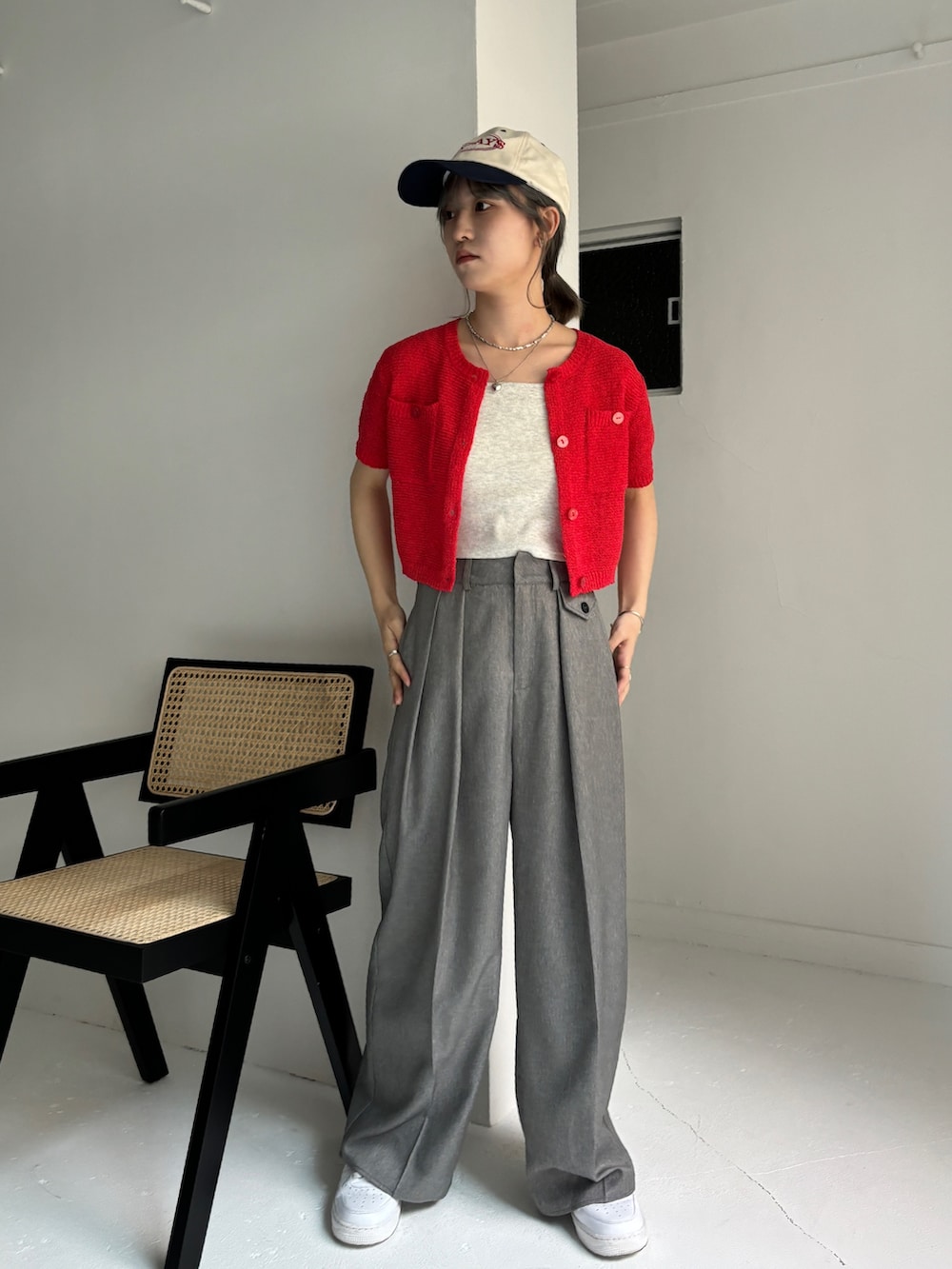 グレー系のスラックス、レッド系のカーディガン/ボレロ、ベージュ系のキャミソールを着用したレディースの夏コーディネートの2枚目の写真