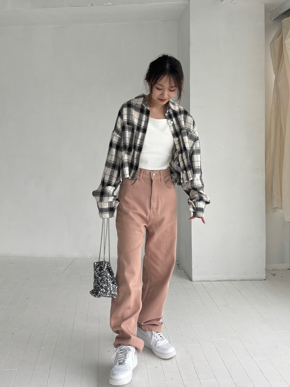 ホワイト系のキャミソール、ピンク系のデニムパンツ、ホワイト系のスニーカーを着用したレディースの秋コーディネートの2枚目の写真