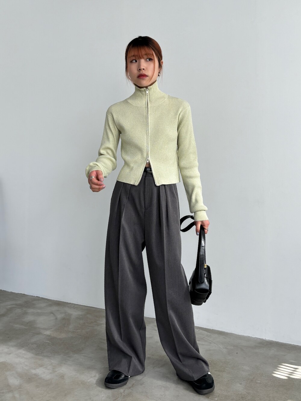 グレー系のスラックス、ブラック系のスニーカー、ベージュ系のニット/セーターを着用したレディースの冬コーディネートの2枚目の写真