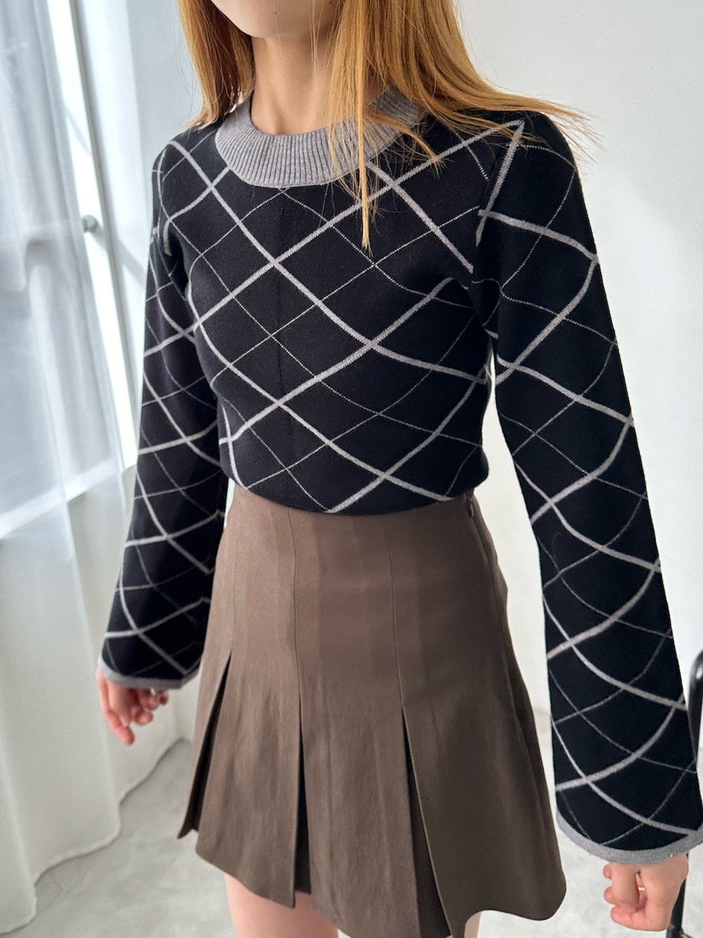 ブラウン系のスカート、ブラック系のニット/セーター、ブラック系のブーツを着用したレディースの冬コーディネートの3枚目の写真