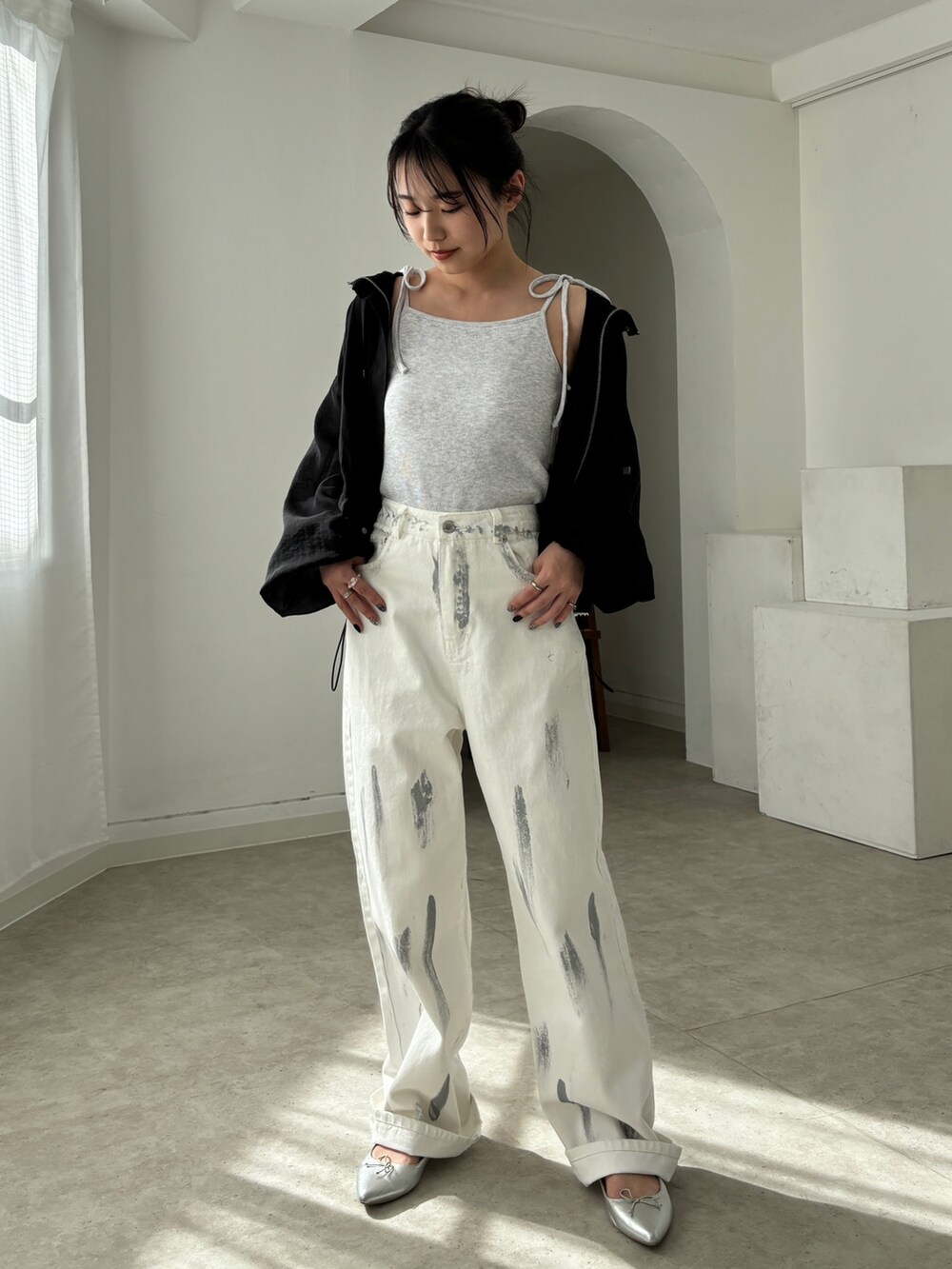 ホワイト系のデニムパンツ、ブラック系のマウンテンパーカー、ベージュ系のキャミソールを着用したレディースの春コーディネートの2枚目の写真