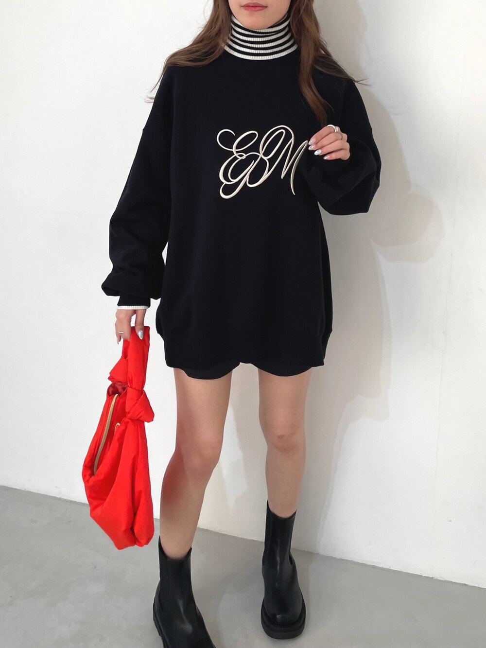 ブラック系のスウェット、ホワイト系のニット/セーター、オレンジ系のハンドバッグを着用したレディースの冬コーディネートの2枚目の写真