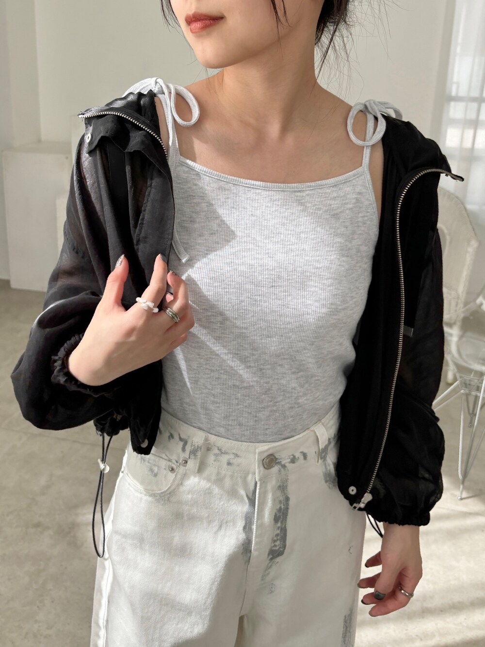 ホワイト系のデニムパンツ、ブラック系のマウンテンパーカー、ベージュ系のキャミソールを着用したレディースの春コーディネートの4枚目の写真