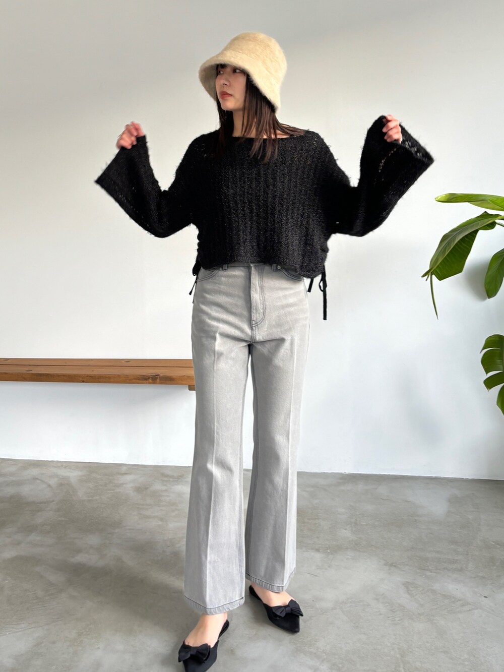 グレー系のデニムパンツ、ブラック系のニット/セーター、ベージュ系のハットを着用したレディースの冬コーディネートの4枚目の写真