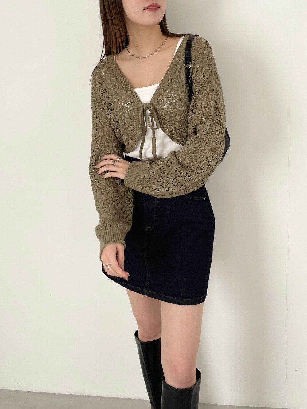 ブルー系のデニムスカート、グリーン系のカーディガン/ボレロ、ブラック系のブーツを着用したレディースの冬コーディネートの2枚目の写真