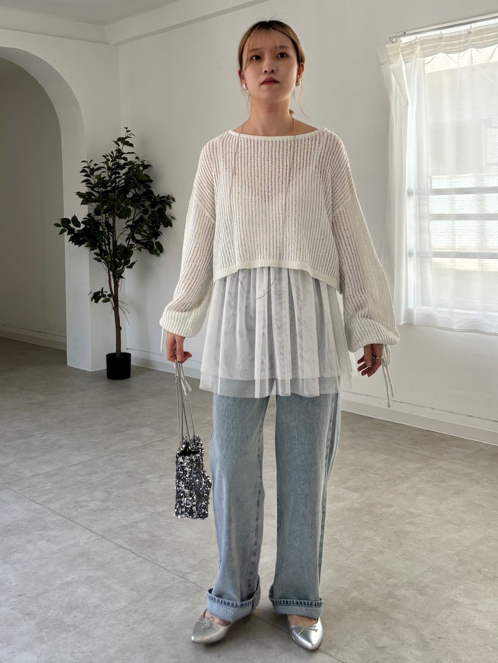 ホワイト系のシャツ/ブラウス、ホワイト系のニット/セーター、ブルー系のデニムパンツを着用したレディースの春コーディネートの2枚目の写真