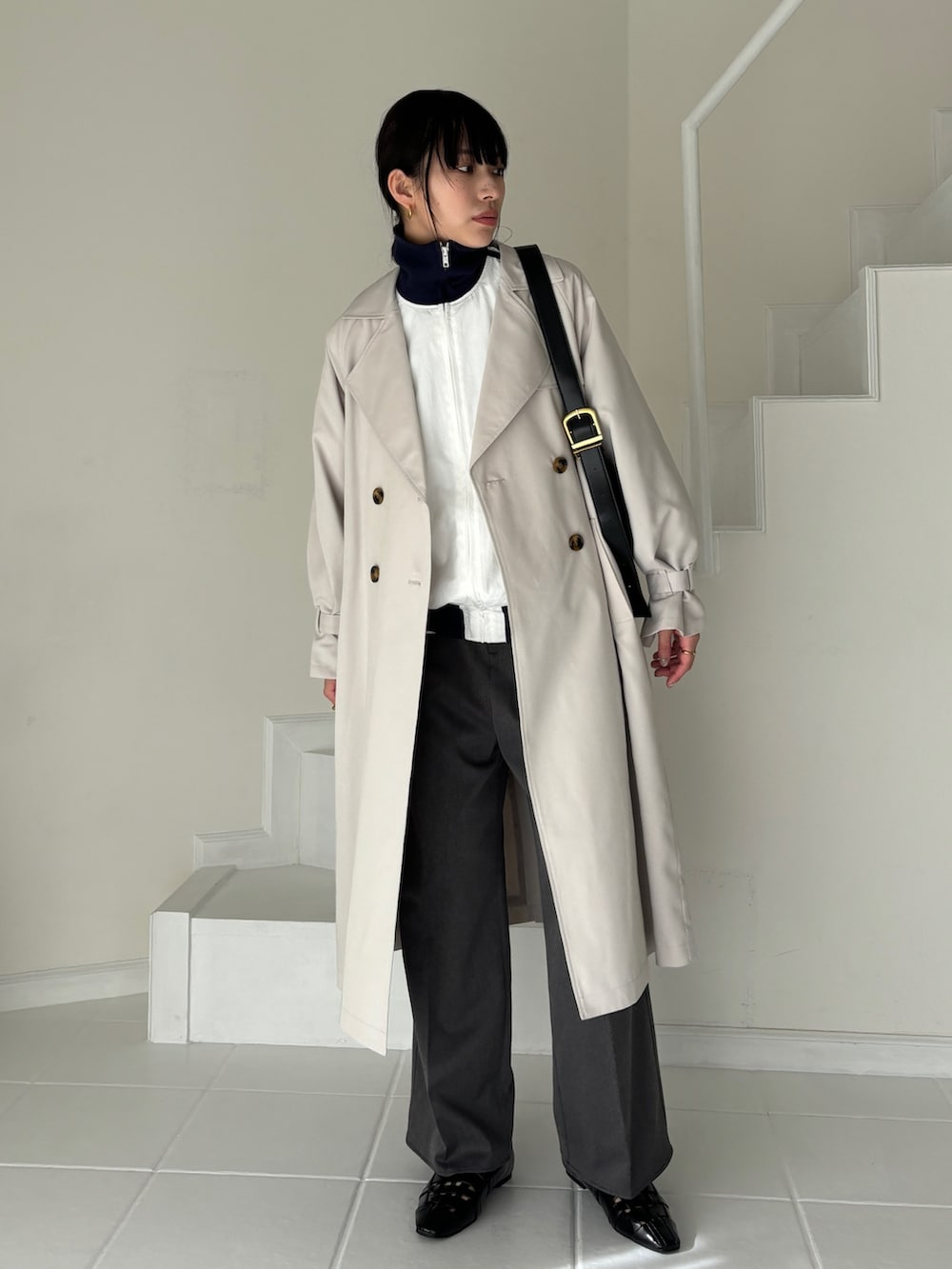 グレー系のトレンチコート、ホワイト系のその他アウター、グレー系のスラックスを着用したレディースの冬コーディネートの2枚目の写真
