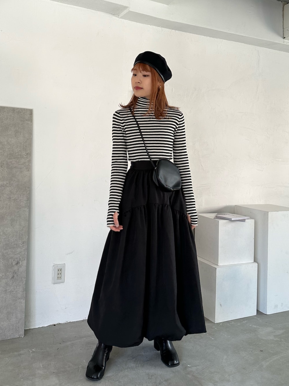 ブラック系のスカート、ブラック系のショルダーバッグ、ブラック系のブーツを着用したレディースの冬コーディネートの2枚目の写真