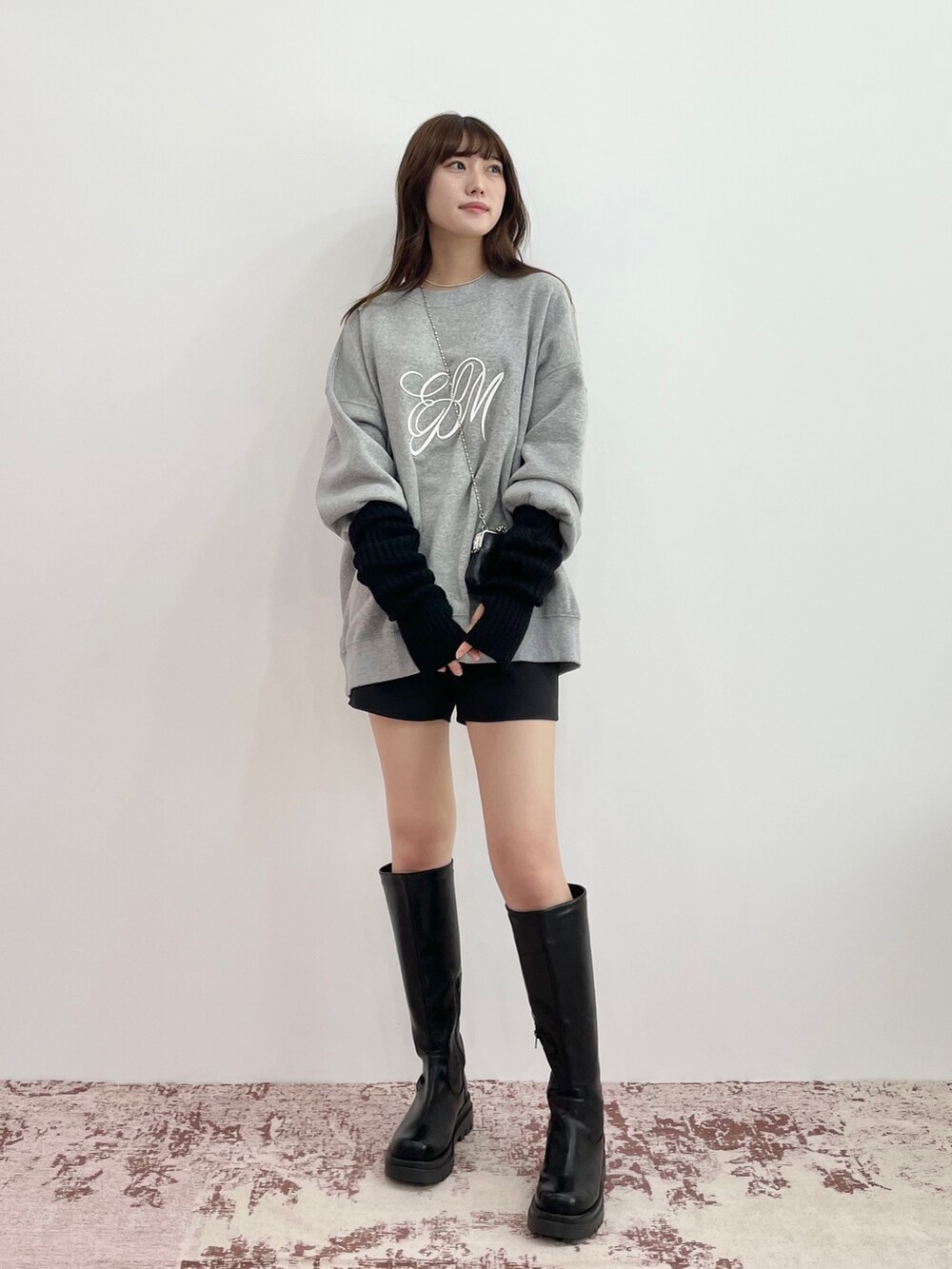 グレー系のスウェット、ブラック系のスカート、ブラック系のブーツを着用したレディースの秋コーディネートの2枚目の写真