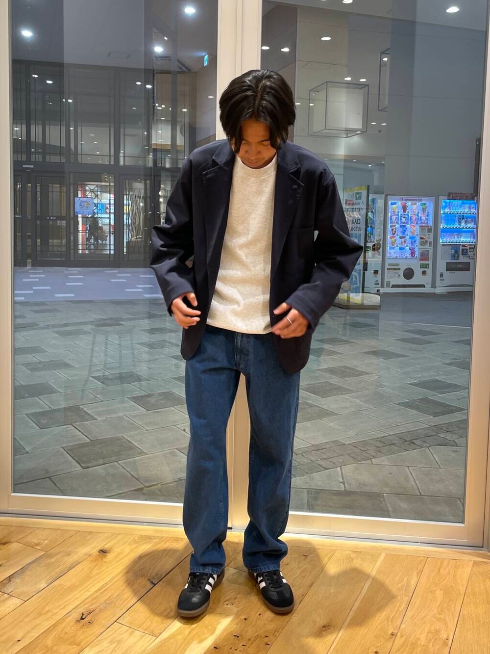 ブルー系のデニムパンツ、グレー系のスウェット、ブラック系のスニーカーを着用したメンズの秋コーディネートの2枚目の写真