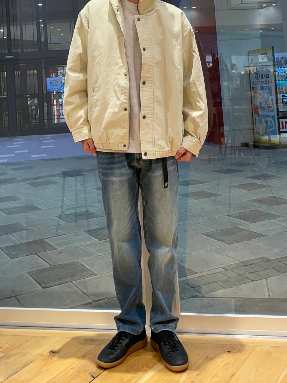 ブルー系のデニムパンツ、ブラック系のスニーカー、ベージュ系のTシャツ/カットソーを着用したメンズの秋コーディネートの5枚目の写真