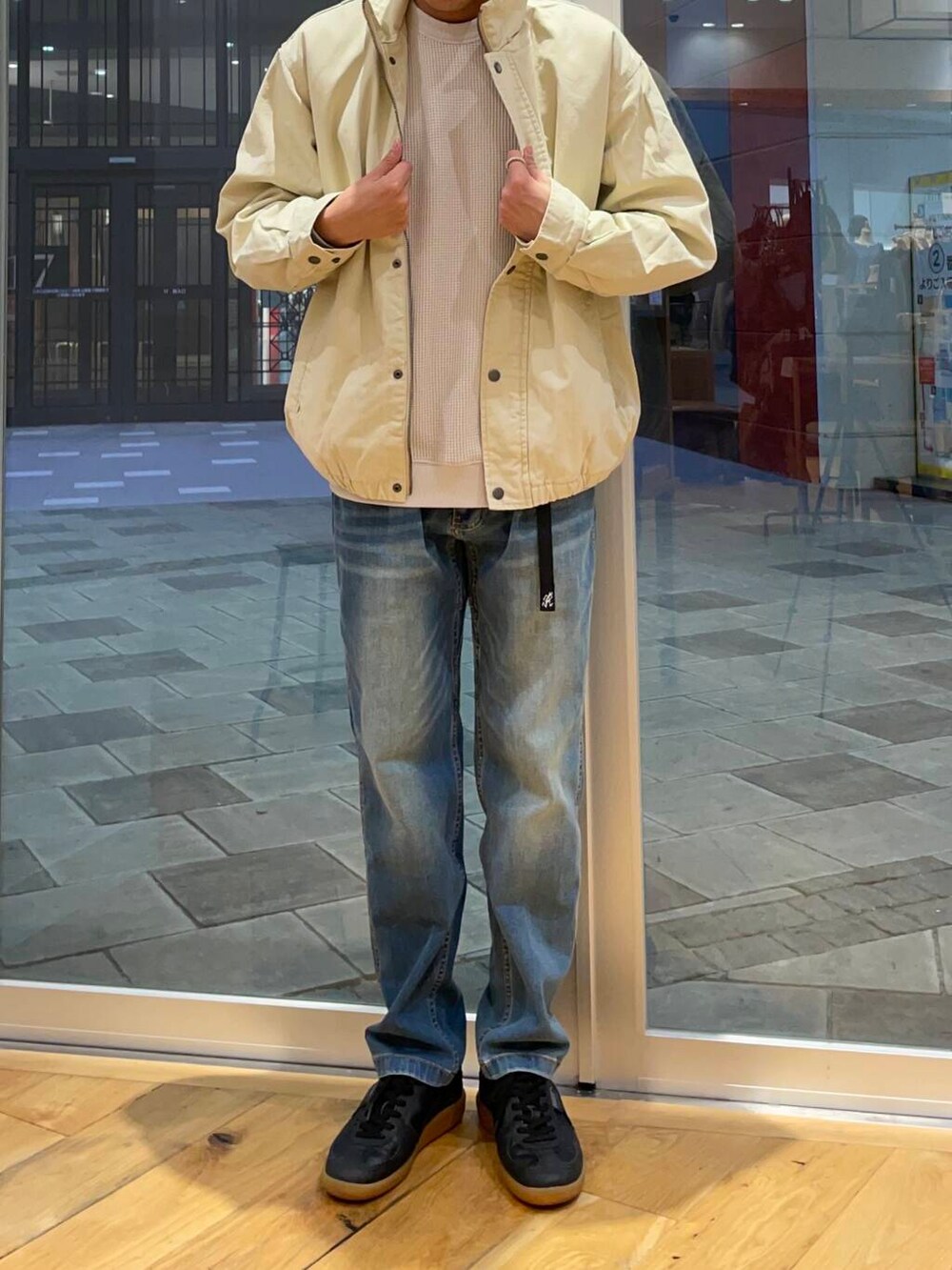 ブルー系のデニムパンツ、ブラック系のスニーカー、ベージュ系のTシャツ/カットソーを着用したメンズの秋コーディネートの2枚目の写真