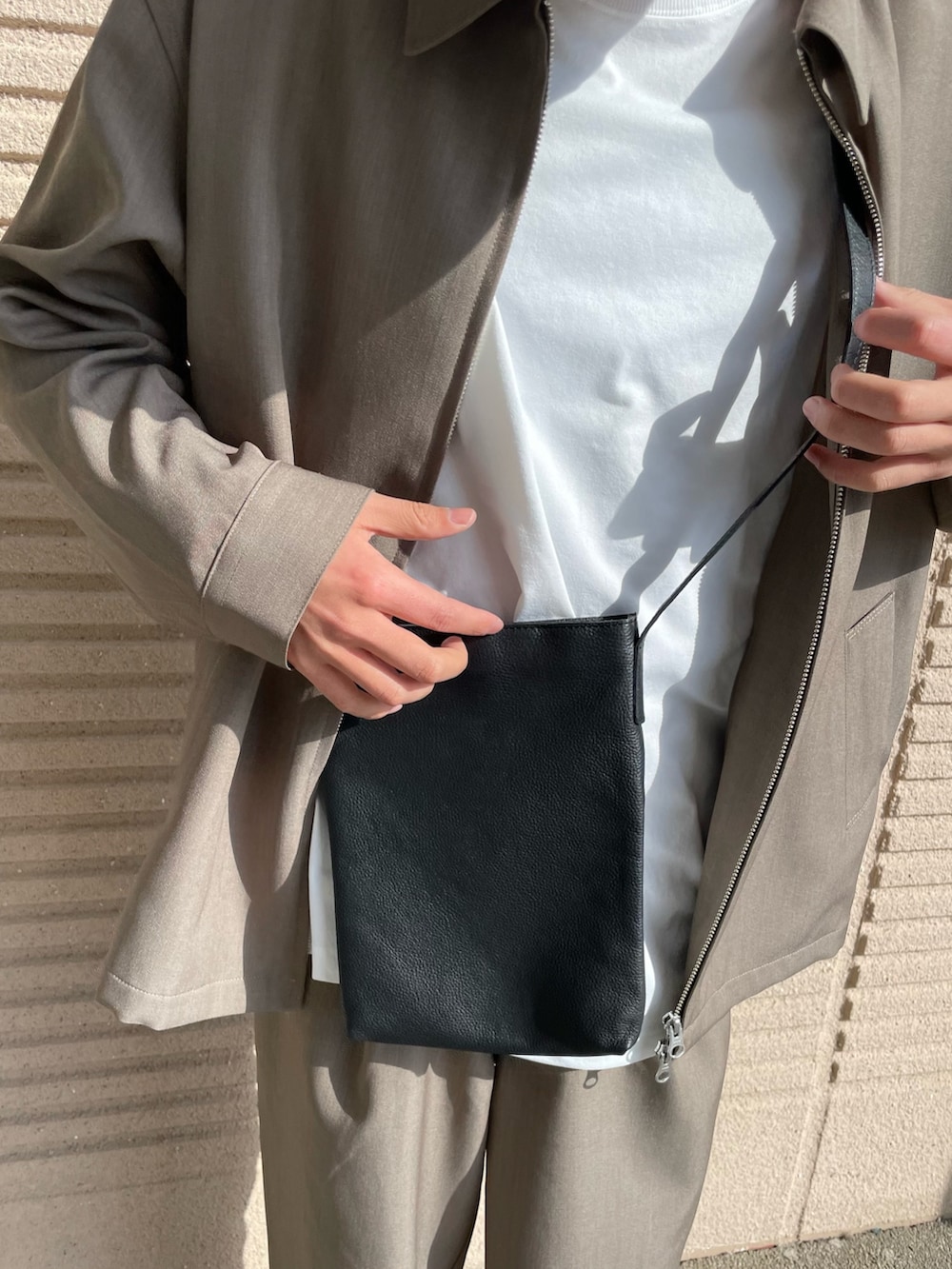 ブラウン系のブルゾン、ブラック系のショルダーバッグ、ホワイト系のTシャツ/カットソーを着用したメンズの春コーディネートの3枚目の写真