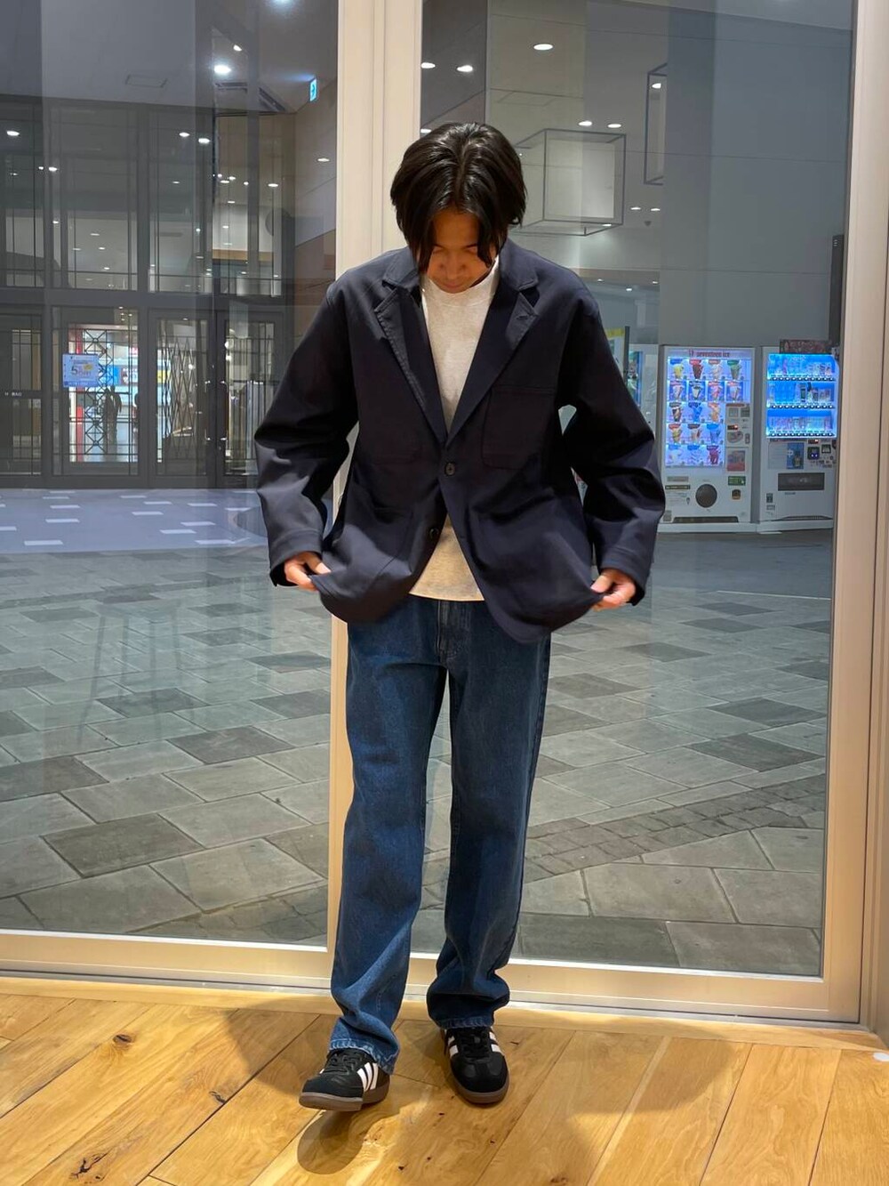 ブルー系のデニムパンツ、グレー系のスウェット、ブラック系のスニーカーを着用したメンズの秋コーディネートの5枚目の写真