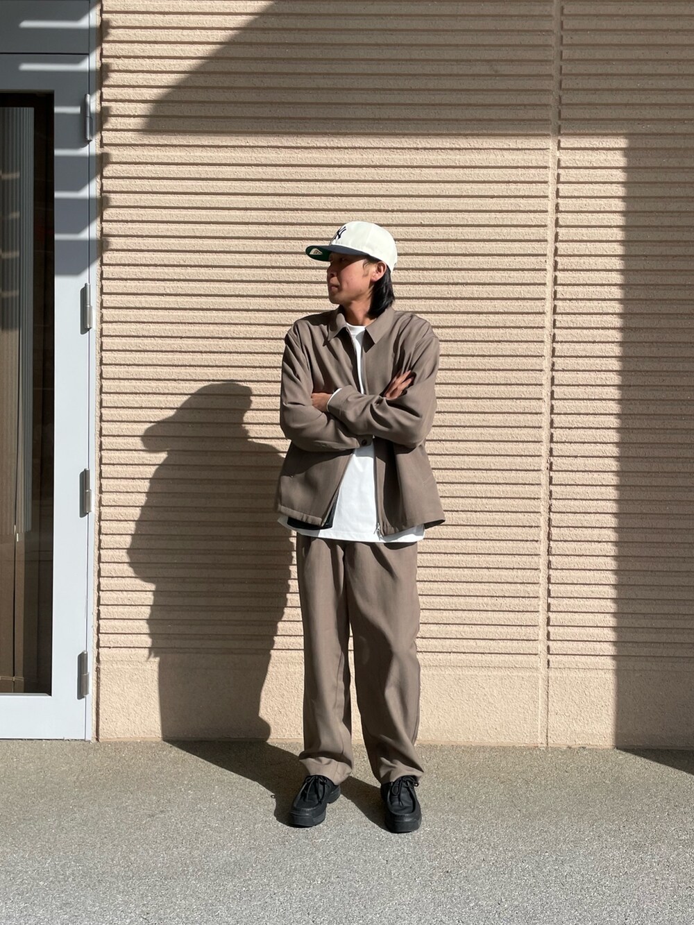 ブラウン系のブルゾン、ブラック系のショルダーバッグ、ホワイト系のTシャツ/カットソーを着用したメンズの春コーディネートの4枚目の写真