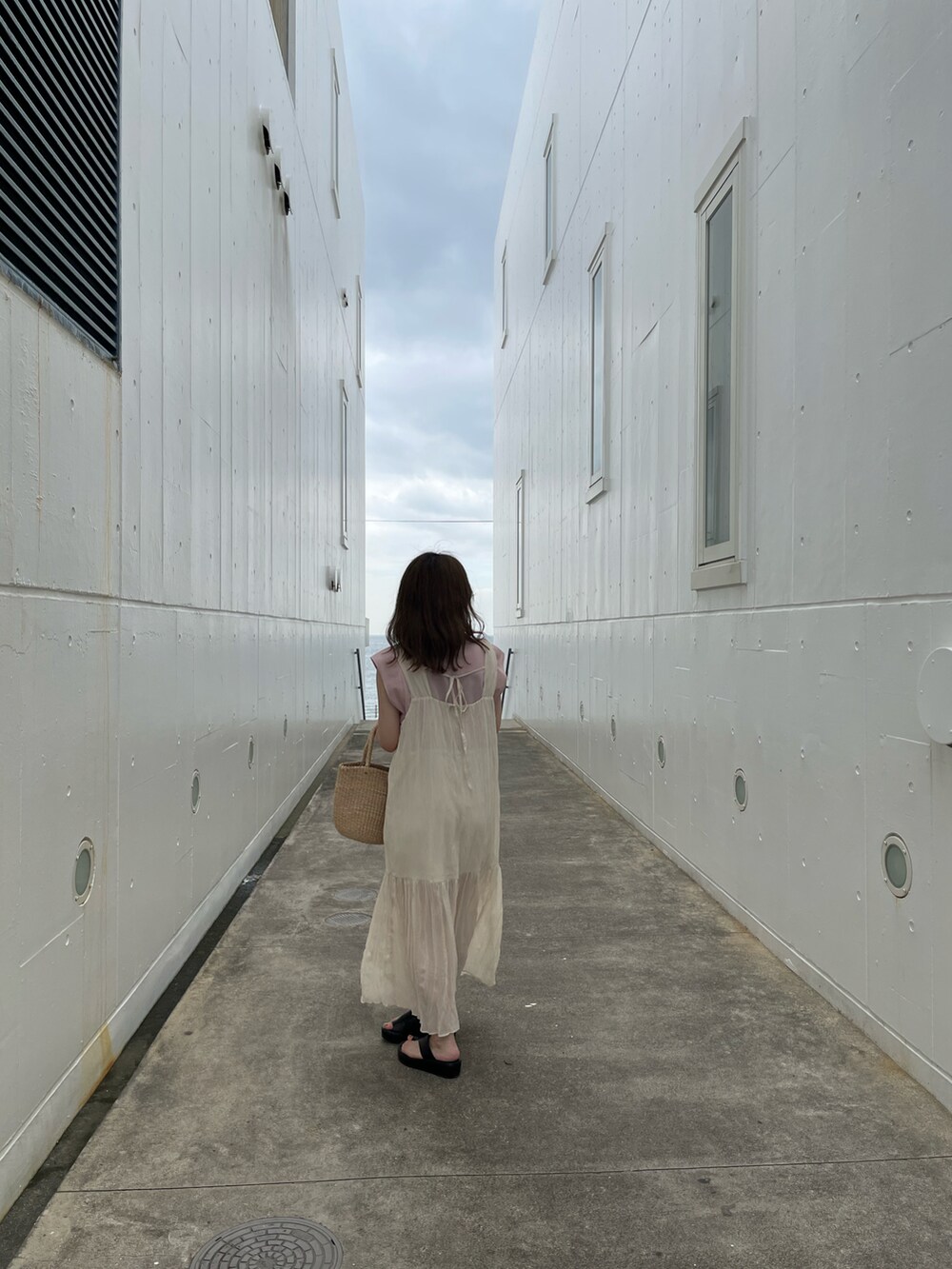 ホワイト系のワンピース、ブラック系のサンダル、ピンク系のタンクトップを着用したレディースの夏コーディネートの2枚目の写真
