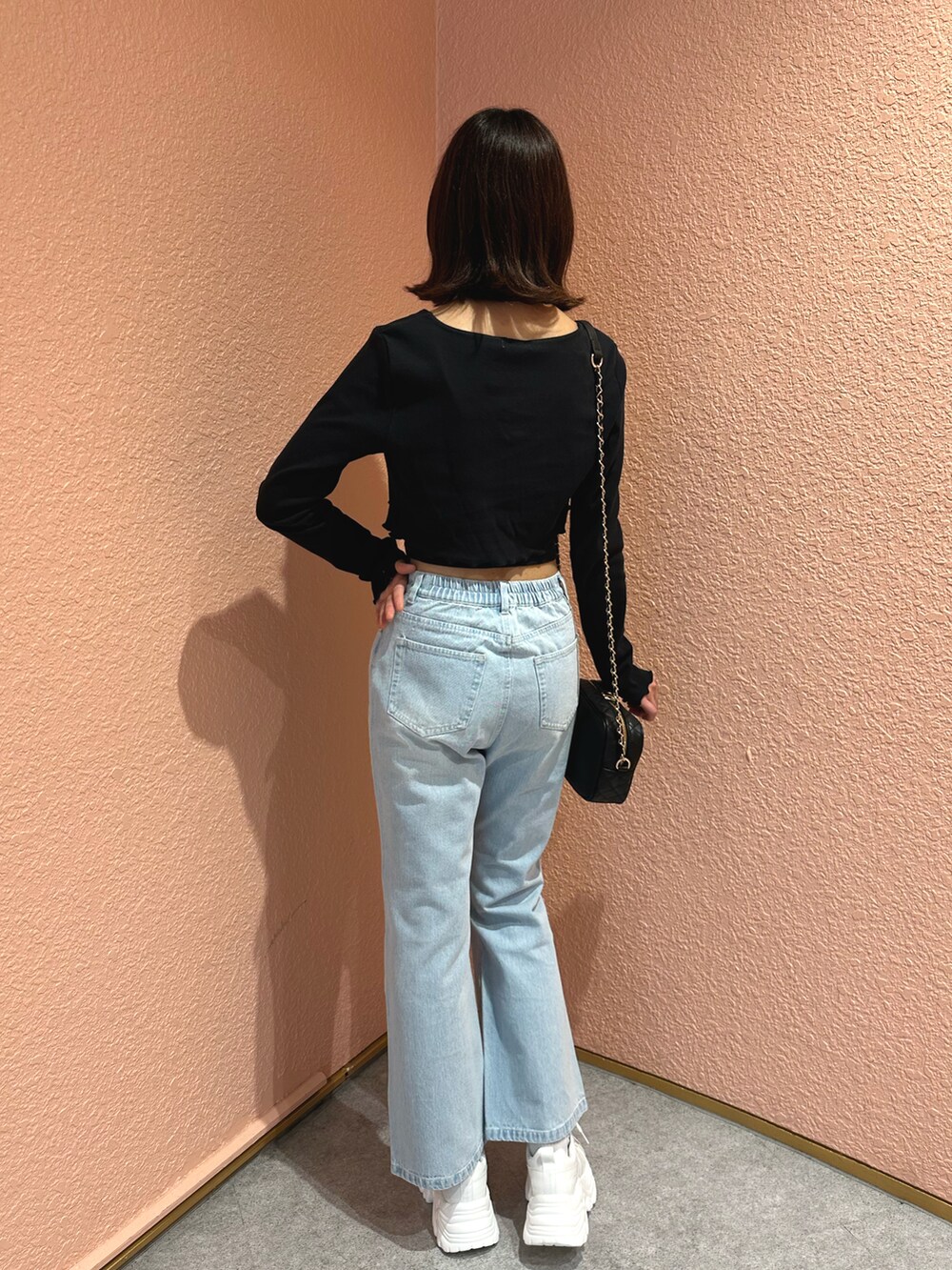 ブラック系のアンサンブル、ブルー系のデニムパンツ、ホワイト系のスニーカーを着用したレディースの春コーディネートの2枚目の写真