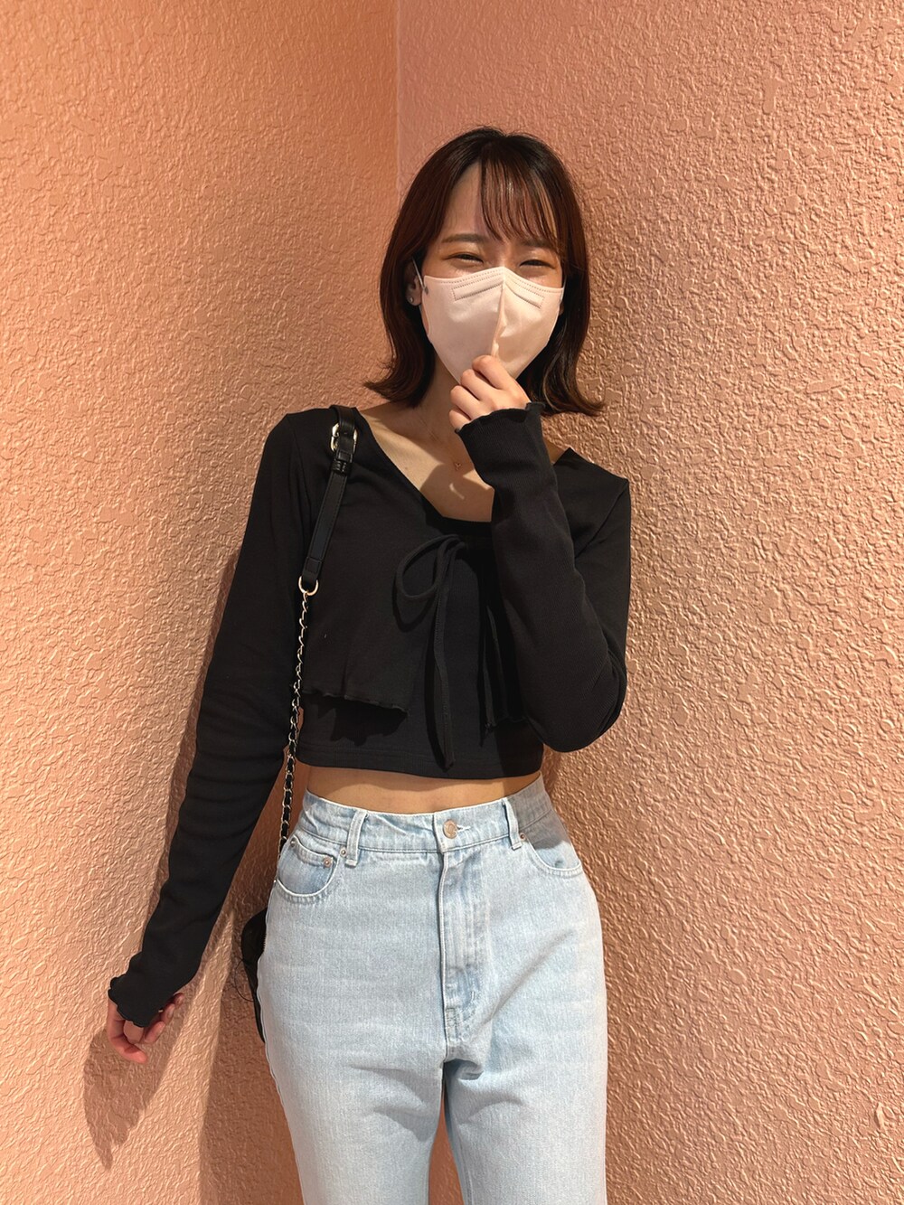 ブラック系のアンサンブル、ブルー系のデニムパンツ、ホワイト系のスニーカーを着用したレディースの春コーディネートの3枚目の写真