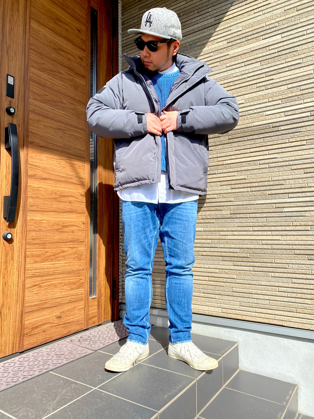 ホワイト系のスニーカー、ブルー系のデニムパンツ、ブルー系のニット/セーターを着用したメンズの冬コーディネートの2枚目の写真