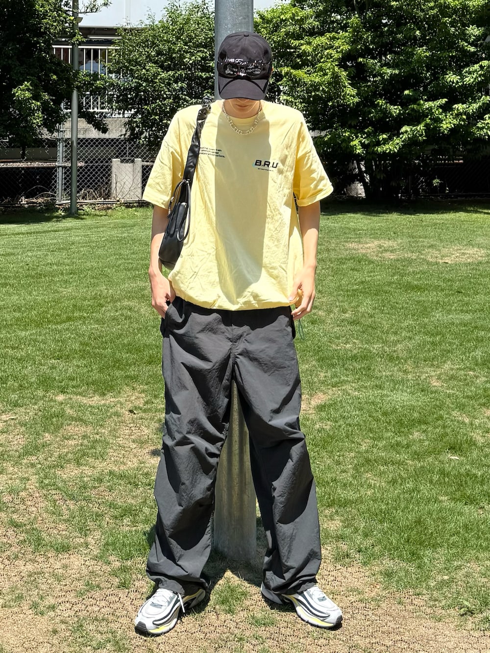 イエロー系のTシャツ/カットソー、ブラック系のカーゴパンツ、ホワイト系のスニーカーを着用したメンズの夏コーディネートの3枚目の写真