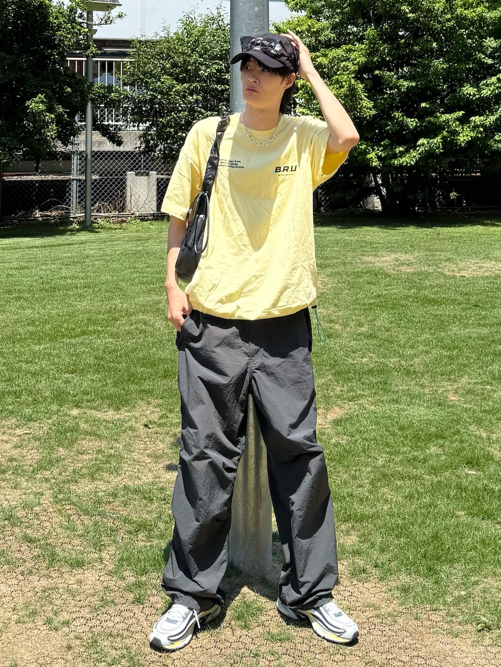 イエロー系のTシャツ/カットソー、ブラック系のカーゴパンツ、ホワイト系のスニーカーを着用したメンズの夏コーディネートの2枚目の写真
