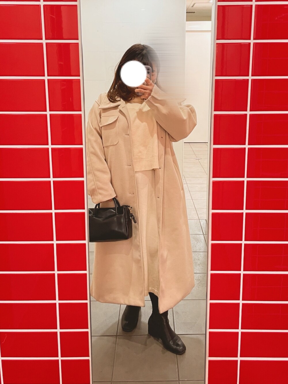 ブラック系のボストンバッグ、ホワイト系のワンピース、ブラック系のブーツを着用したレディースの冬コーディネートの2枚目の写真