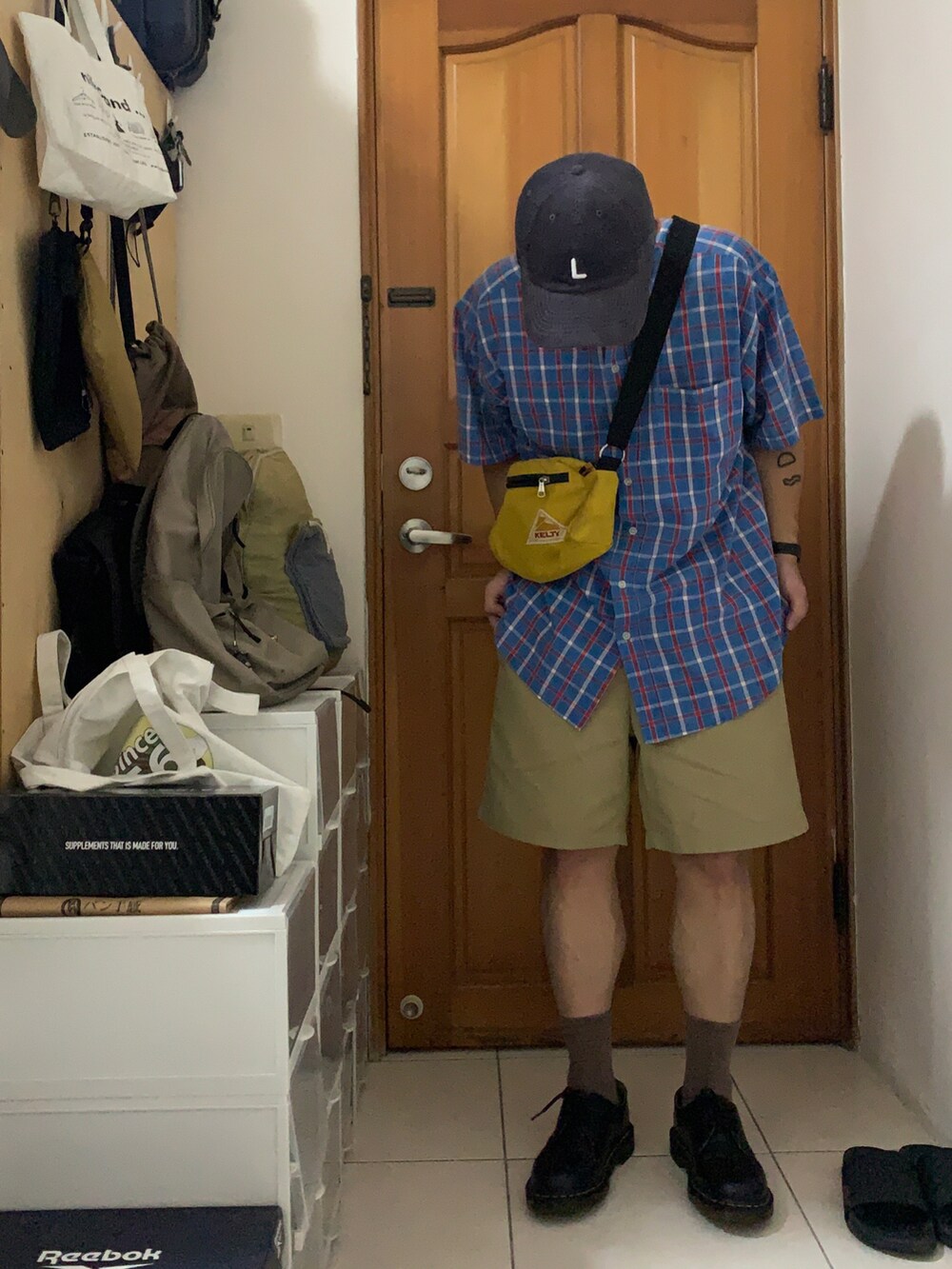 ベージュ系のカーゴパンツ、イエロー系のメッセンジャーバッグ、グレー系のキャップを着用したメンズの夏コーディネートの2枚目の写真