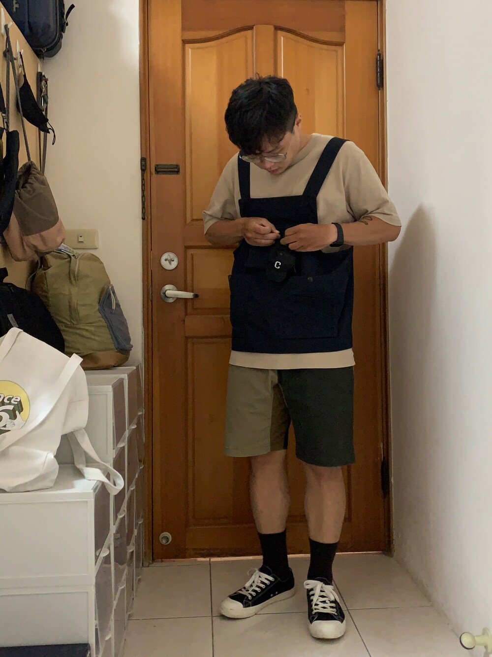 ブラック系のベスト、ブラウン系のカーゴパンツ、ブラック系のコインケースを着用したメンズの夏コーディネートの2枚目の写真