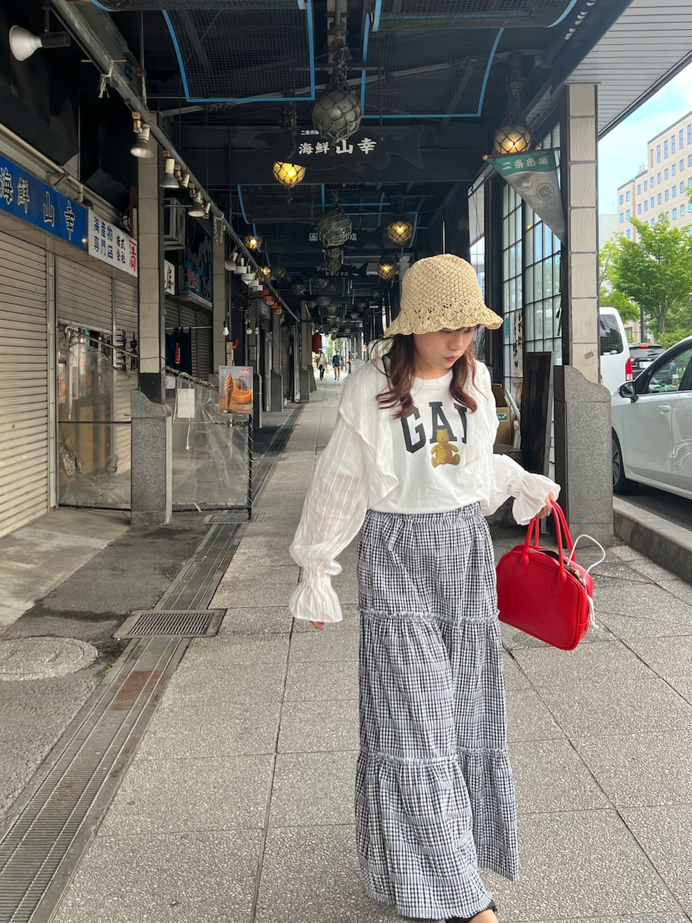 レッド系のボストンバッグ、ブラック系のスカート、ホワイト系のカーディガン/ボレロを着用したレディースの夏コーディネートの2枚目の写真