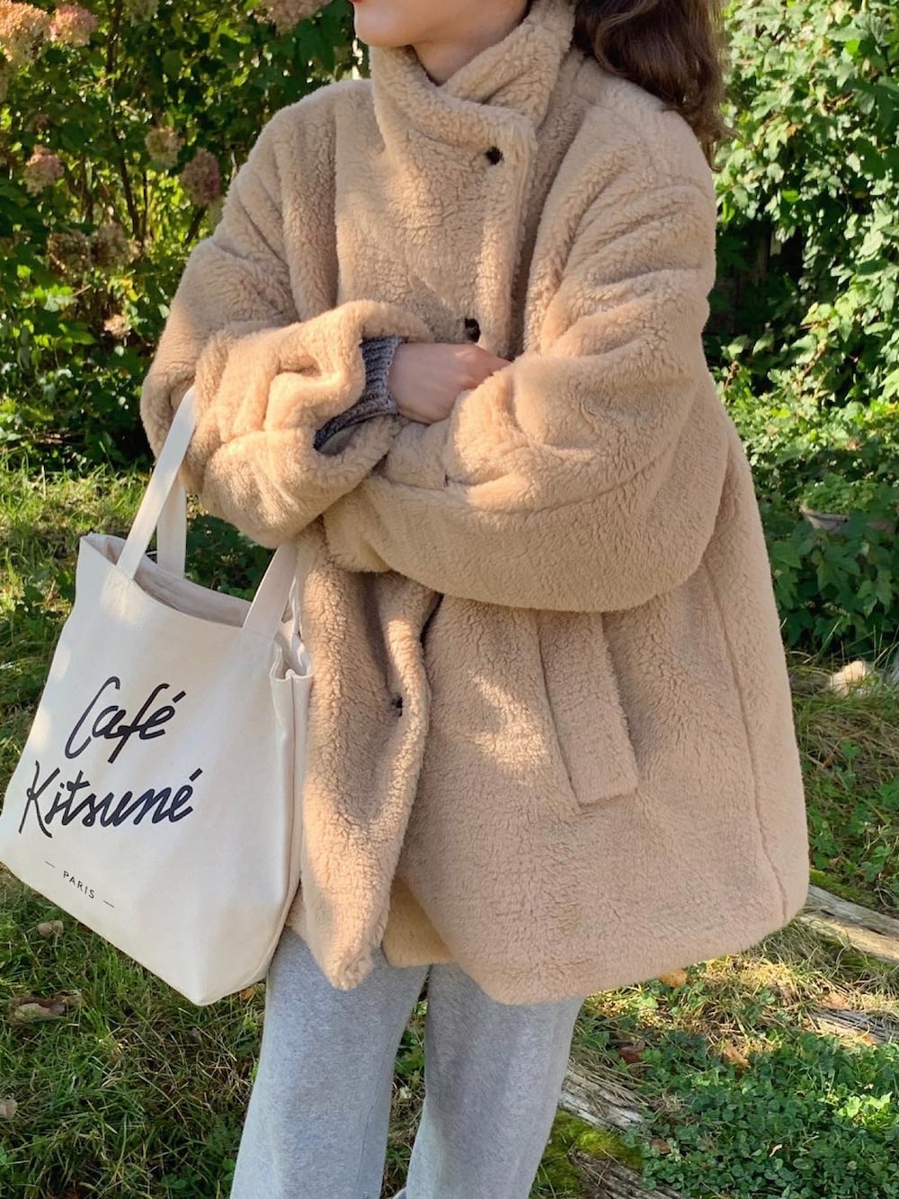 ベージュ系のダッフルコート、ホワイト系のトートバッグ、グレー系のスウェットパンツを着用したレディースの秋コーディネートの3枚目の写真