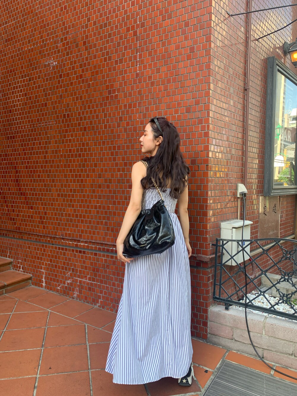 ブラック系のショルダーバッグ、ホワイト系のワンピース/ドレス、ブラック系のシューズを着用したレディースの春コーディネートの2枚目の写真