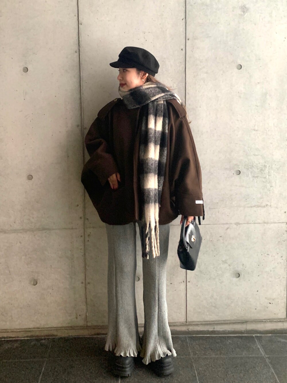 ブラック系のブーツ、グレー系のその他パンツ、ブラウン系のノーカラーコートを着用したレディースの冬コーディネートの2枚目の写真