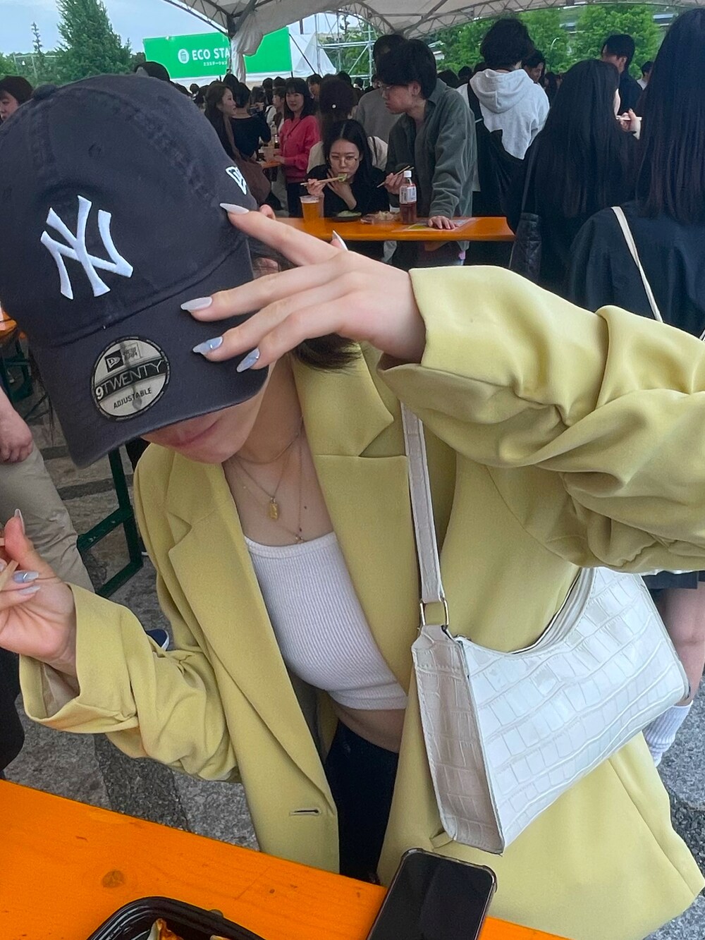 イエロー系のテーラードジャケット、ブルー系のデニムパンツ、ホワイト系のサンダルを着用したレディースの秋コーディネートの2枚目の写真