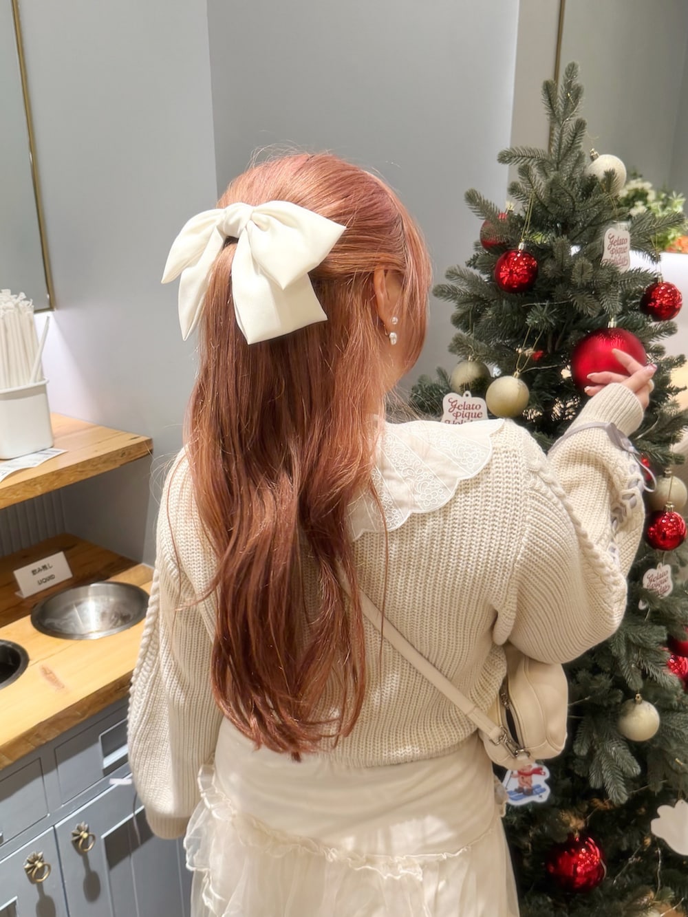 ホワイト系のニット/セーター、ホワイト系のスカート、ホワイト系のショルダーバッグを着用したレディースの冬コーディネートの3枚目の写真